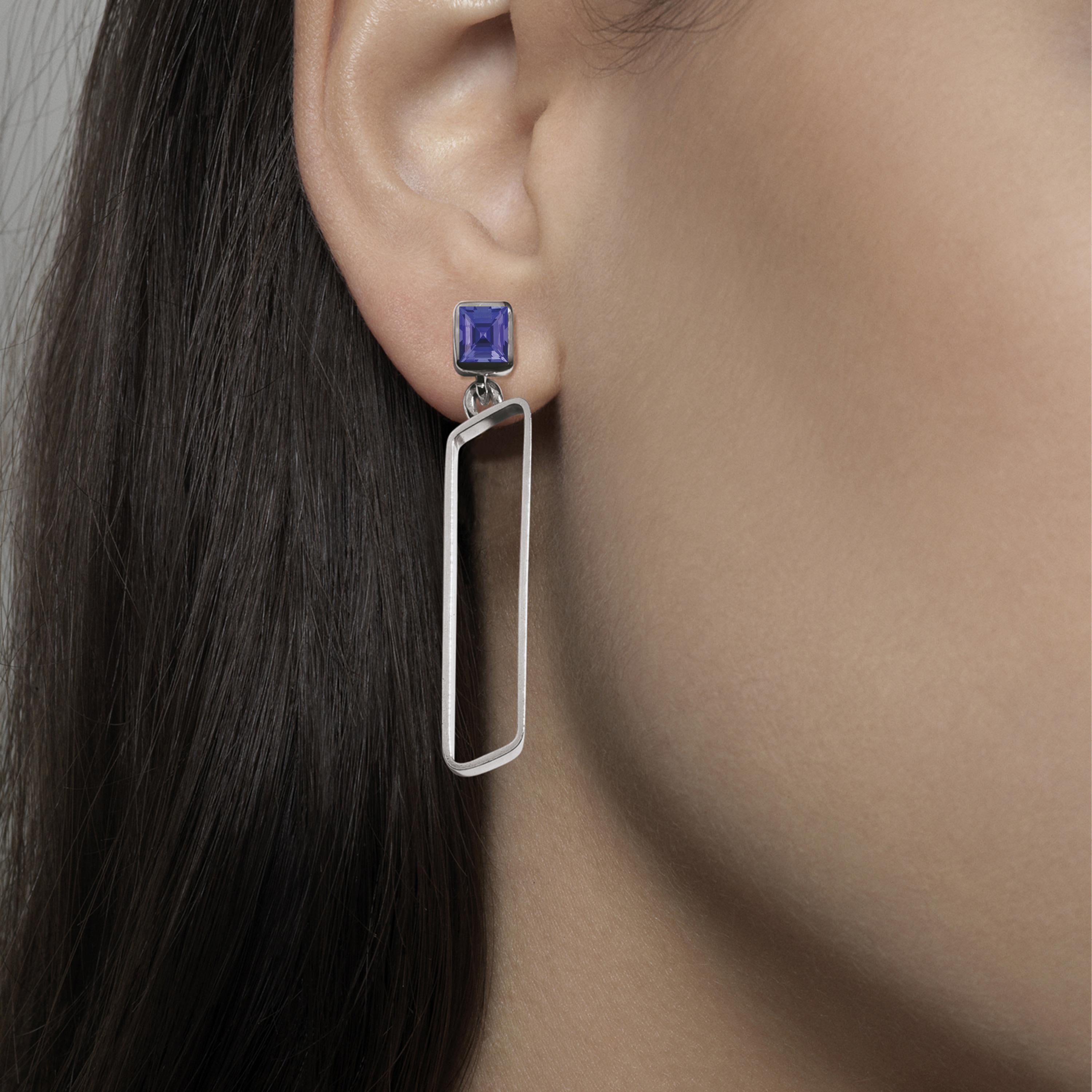 Made by hand in Nathalie Jean's Milan atelier in limited edition, the Saphir Infini drop dangle earrings are composed of polished sterling silver ribbon shapes with rounded edges and square cut iolite. The angular configurations of the sapphire’s