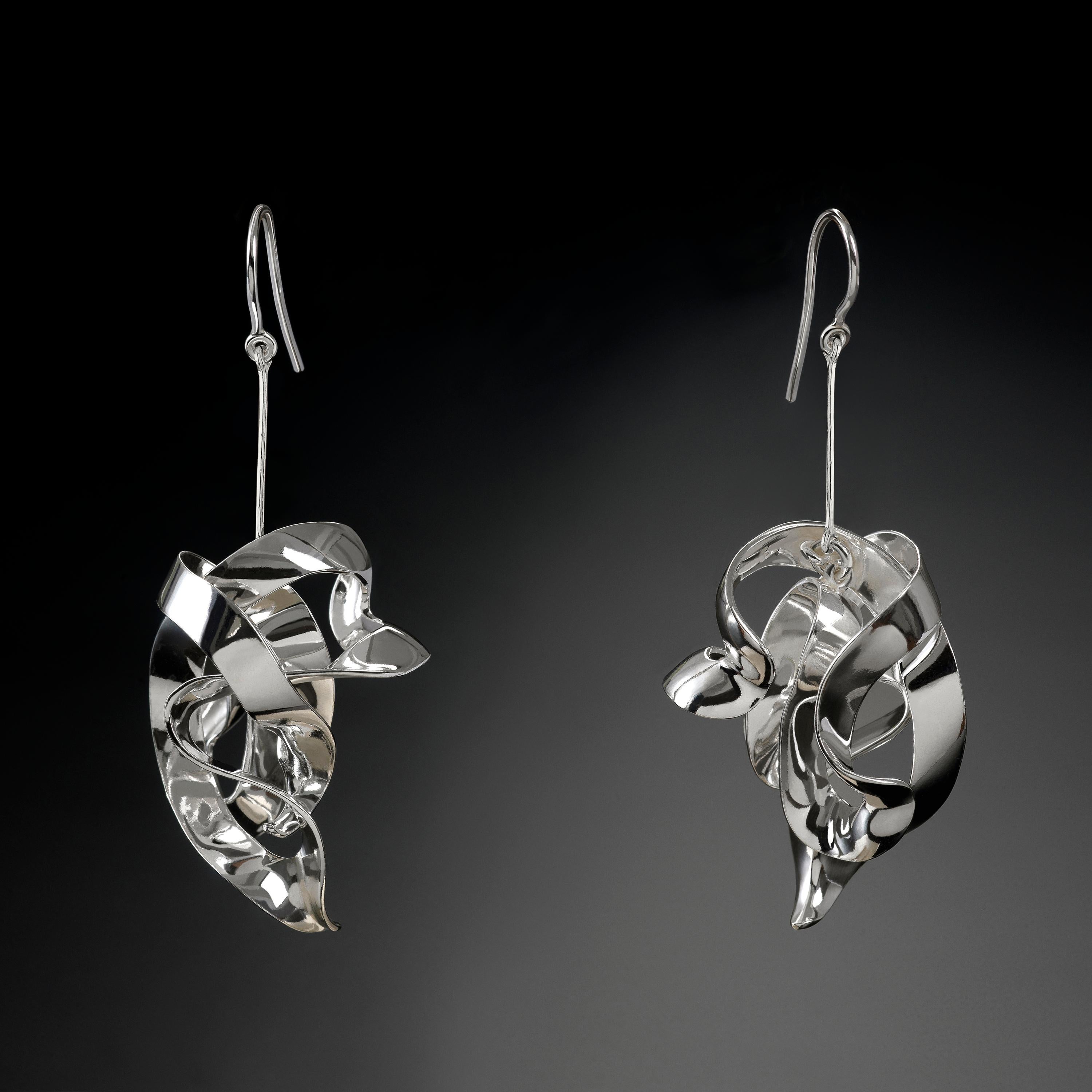 With their delicate, curved, free-form surfaces, the elements of these contemporary jewel-sculptures fold and unfold with harmony and grace like shell fragments or metallised leaves. Intertwined cleverly, the undulating sterling silver pieces dangle