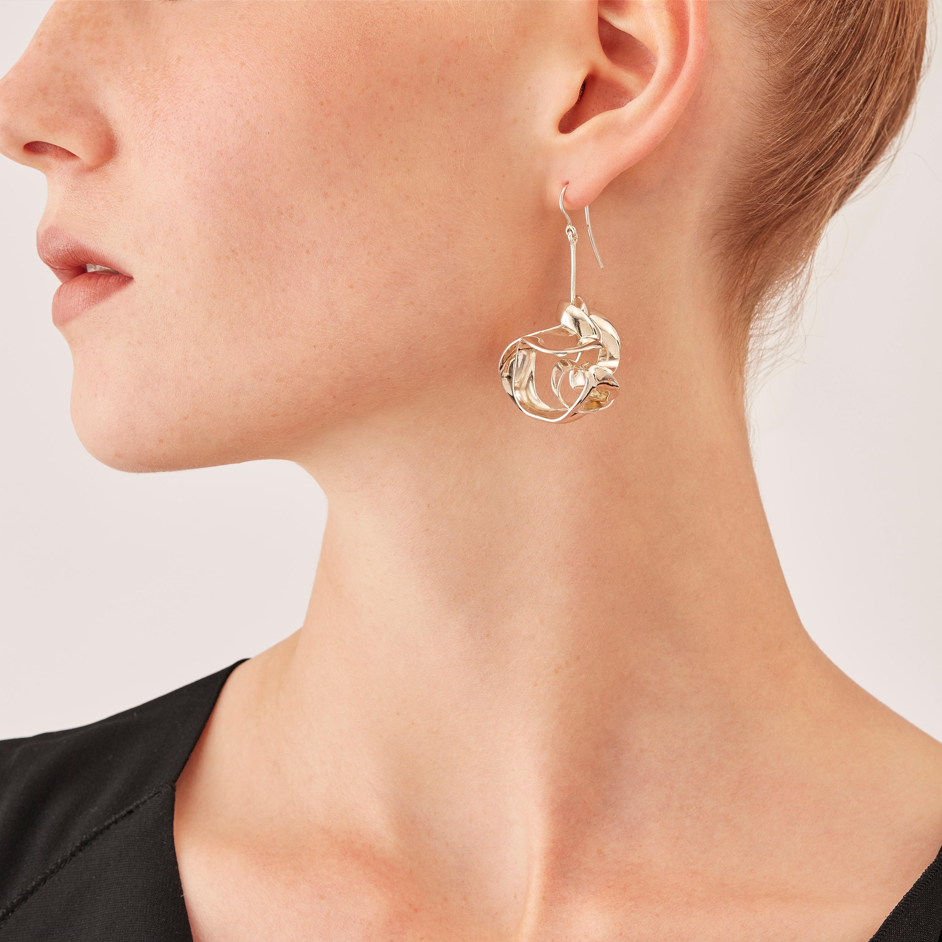 With their delicate, curved, free-form surfaces, the elements of these contemporary sculpture earrings fold and unfold with harmony and grace like glittering shell fragments or polished metallized leaves. Intertwined cleverly, two sophisticated