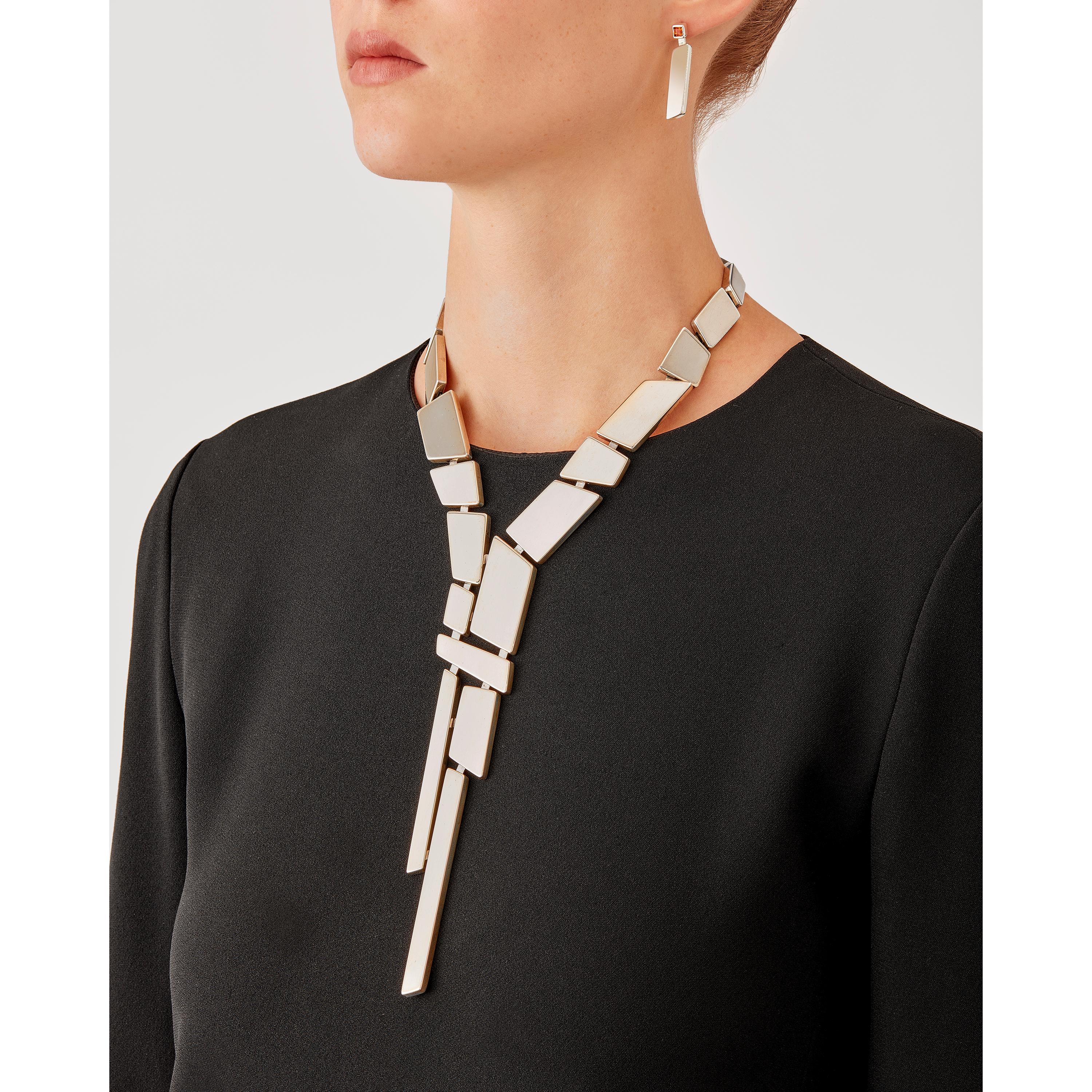 Die in limitierter Auflage im Mailänder Atelier von Nathalie Jean handgefertigte Krawattenkette Saphir Absolu besteht aus leichten geometrischen Hohlkörpern mit abgerundeten Kanten aus Sterlingsilber. Dank raffinierter, versteckter Glieder lassen