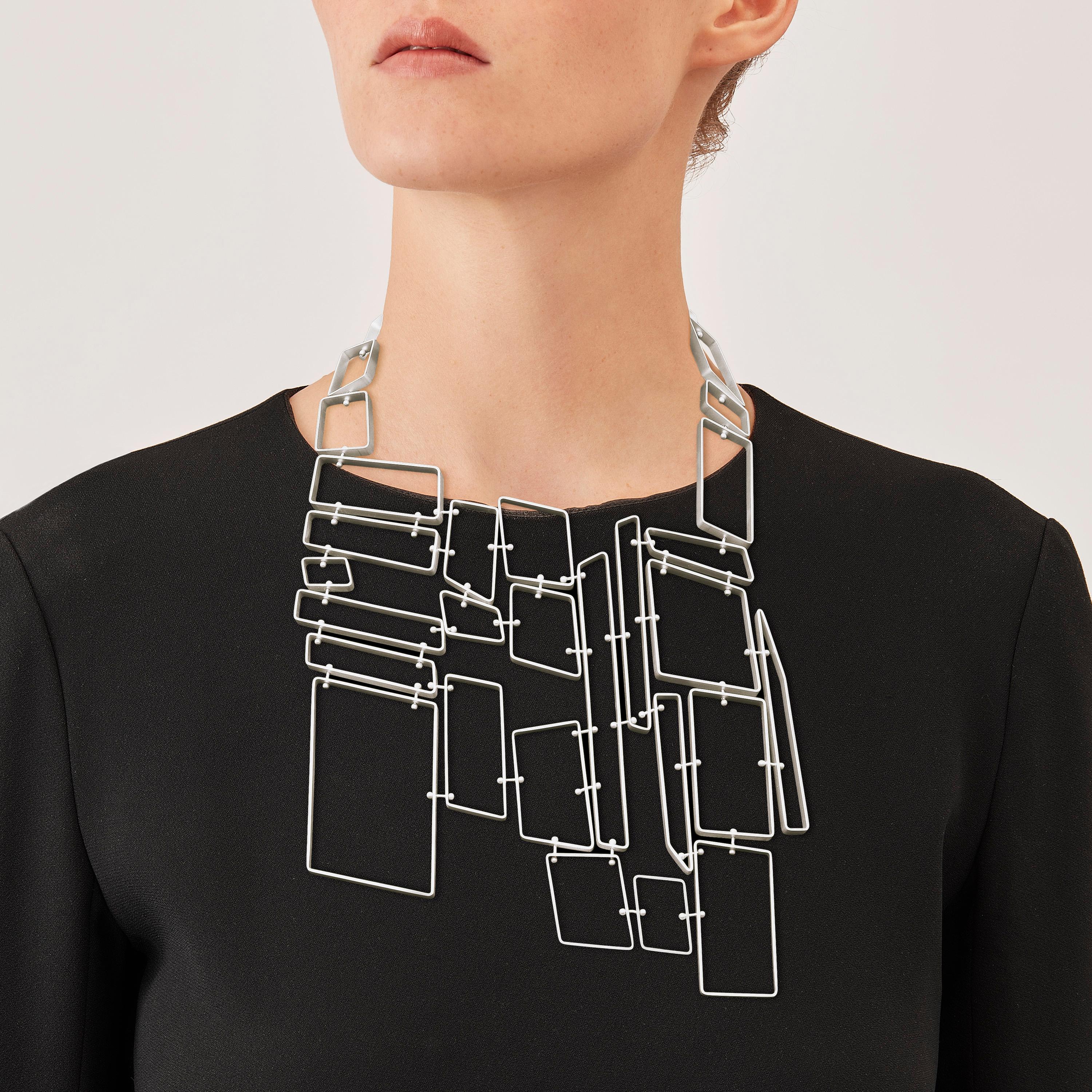 Made by hand in Nathalie Jean's Milan atelier in limited edition, the Saphir Infini Pectoral contemporary drop necklace is composed of matt sterling silver ribbon shapes with rounded edges. Clever hidden links allow the pieces to drape nicely around