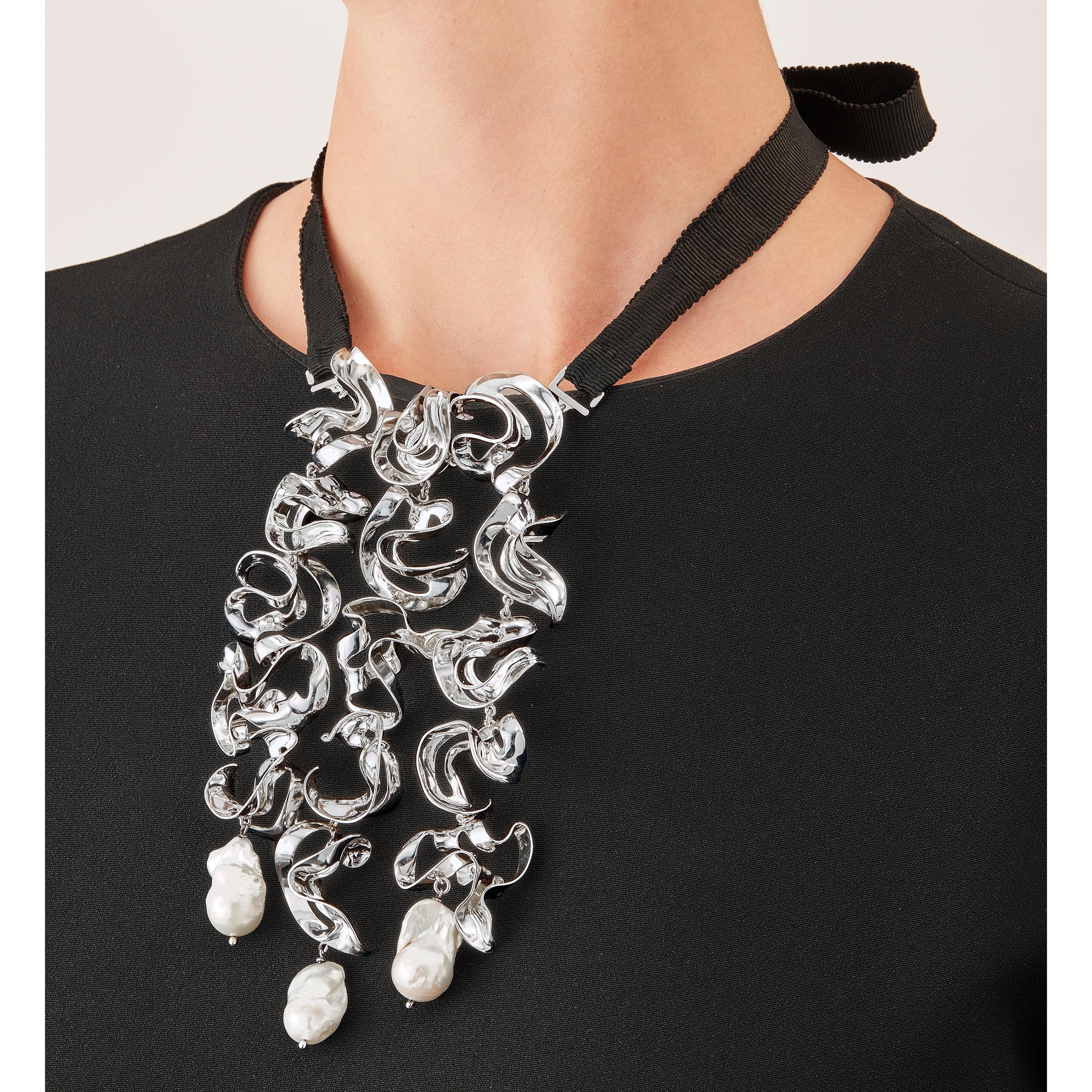 With their delicate, curved, free-form surfaces, the fifteen elements of this contemporary sculpture necklace fold and unfold with harmony and grace like glittering shell fragments or polished metalized leaves. Linked to each other to form a