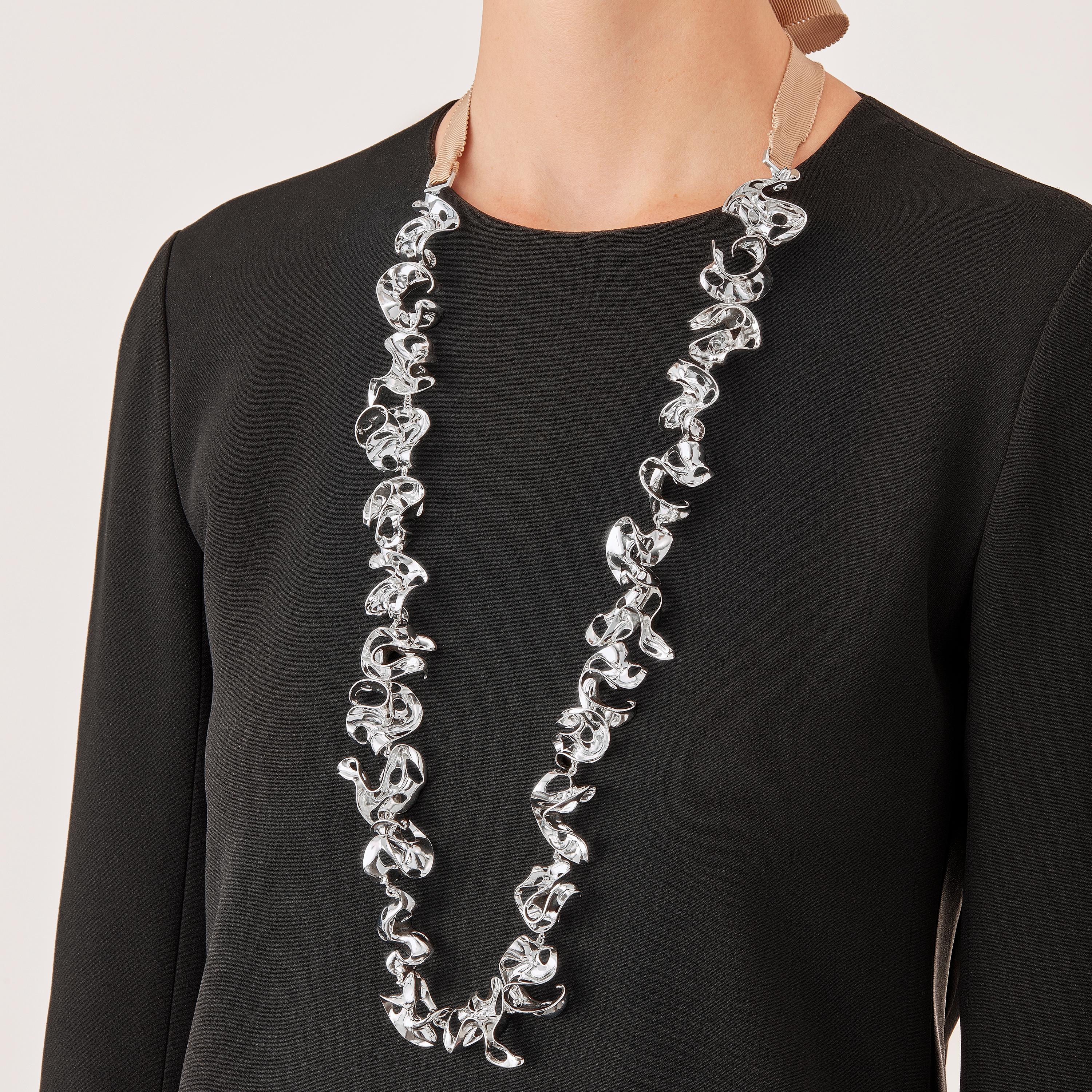 With their delicate, curved, free-form surfaces, the twenty five elements of this contemporary sculpture necklace fold and unfold with harmony and grace like glittering shell fragments or polished metalized leaves. Linked to one another by means of