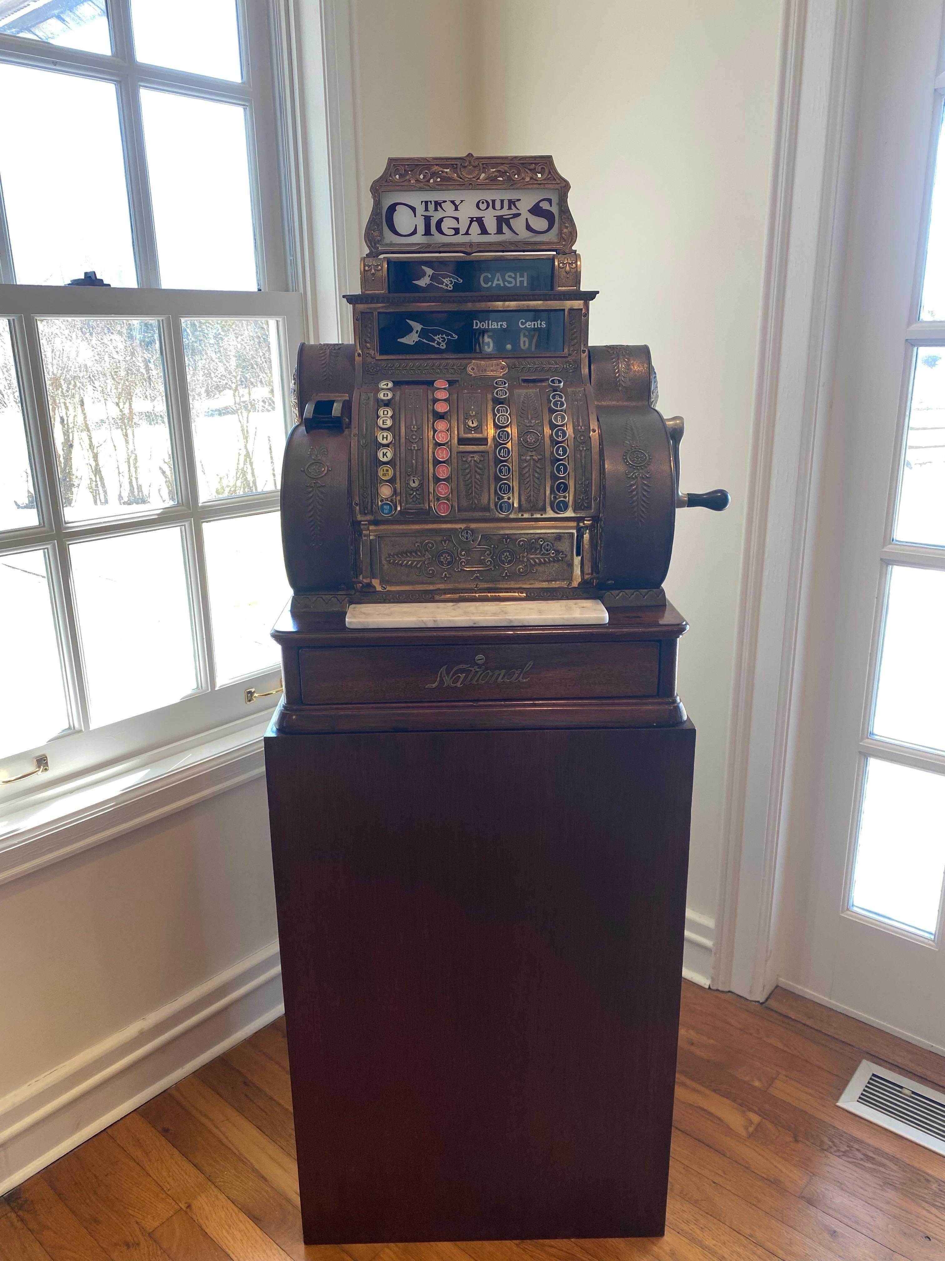 National Cash Register Co. Brass Cash Register, Model 442-E-L, Early 1900s, on wooden plinth.
American. Brass. In 1908, National introduced a new numbering system that grouped their various designs into classes. This brass register, assembled in the