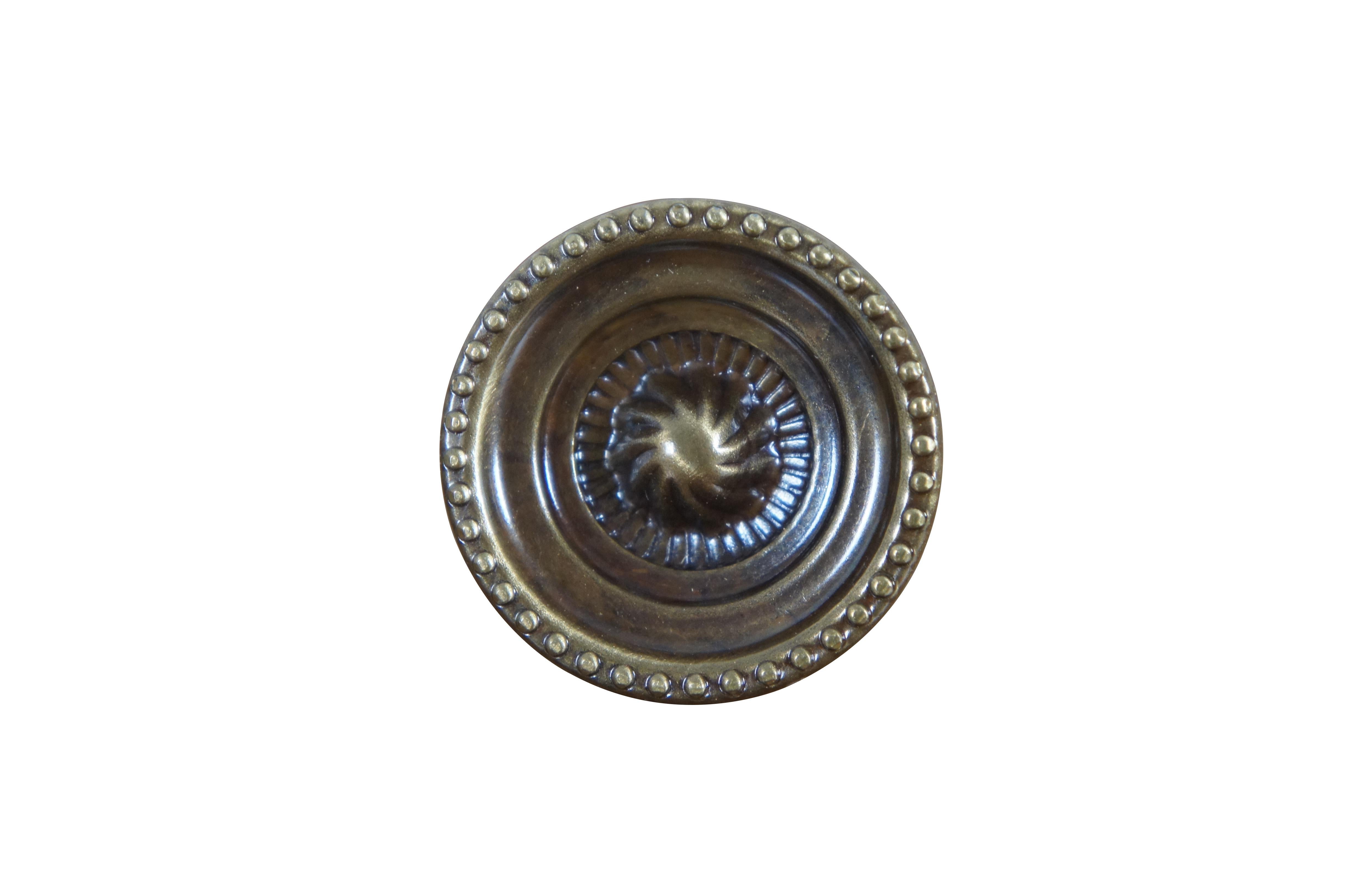 31 Available - Mid to late 20th century old-stock drawer / cabinet pulls. National Lock Company - Medalist, item number C606-4A Knob. Antique brass finish. Round / circular shape with spiral sunburst at center, framed in concentric grooves and