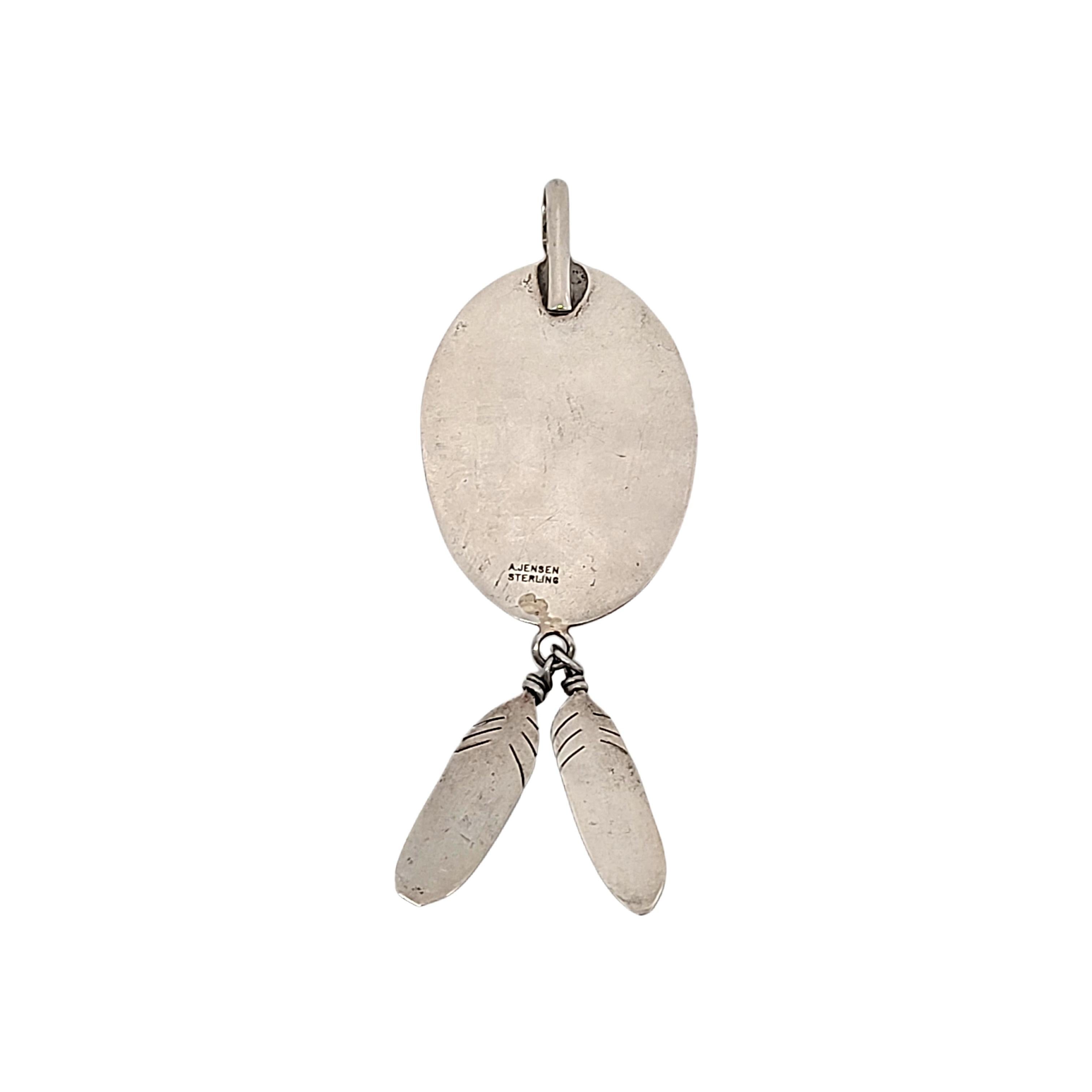 Colgante de pata de oso de plata de ley con turquesa y colgantes de plumas, obra del artesano navajo A. Jensen.

Colgante grande de plata de ley con forma de pata de oso en un diseño de caja de sombras con una turquesa engastada en bisel de diente