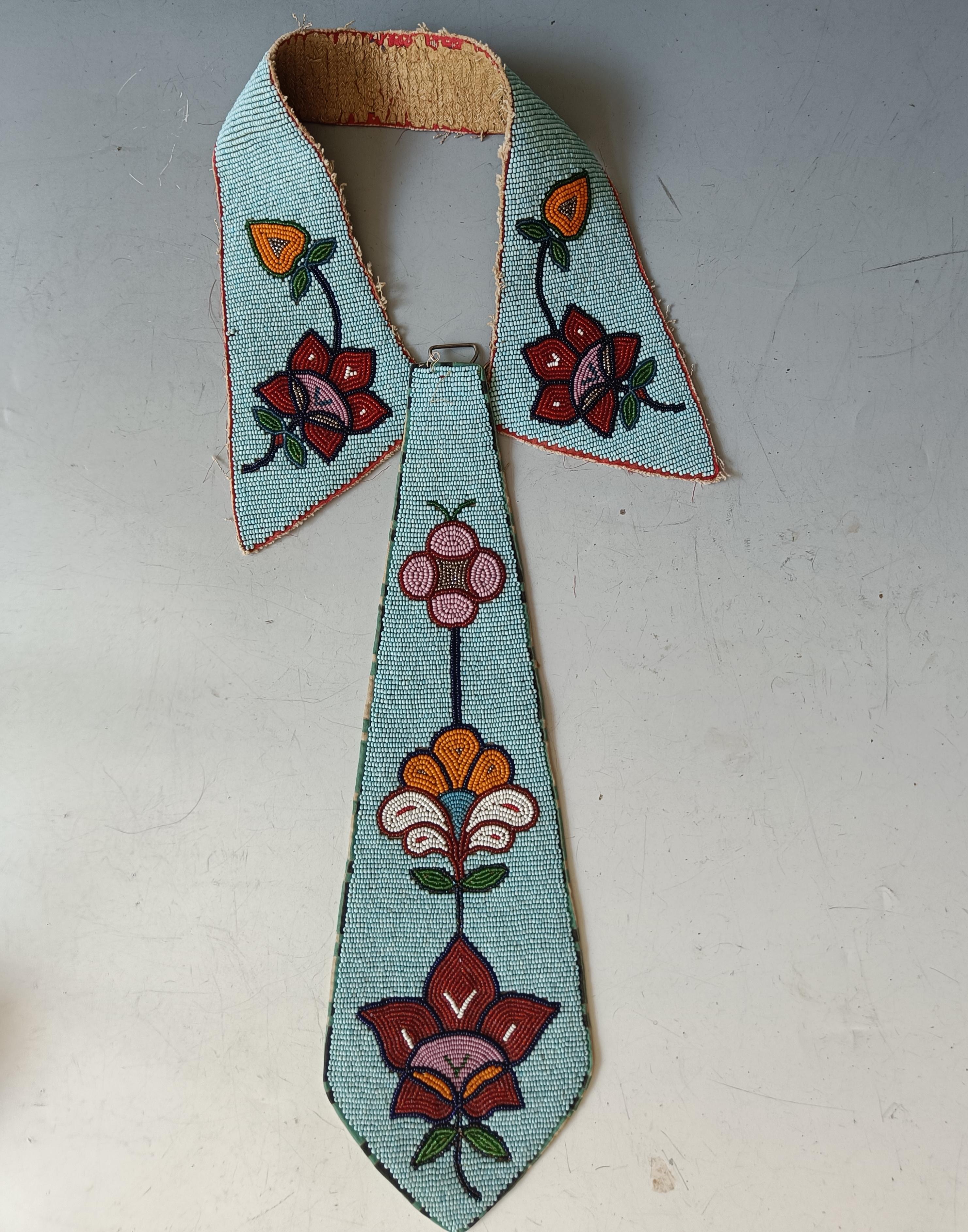 Native American Antique Beaded Collar Tie plateau Nez pierce
A superb antique native American collar and tie crafted in buckskin decorated with beaded floral motives sewn with thread and sinew.
Period  Early 20th century 
 
