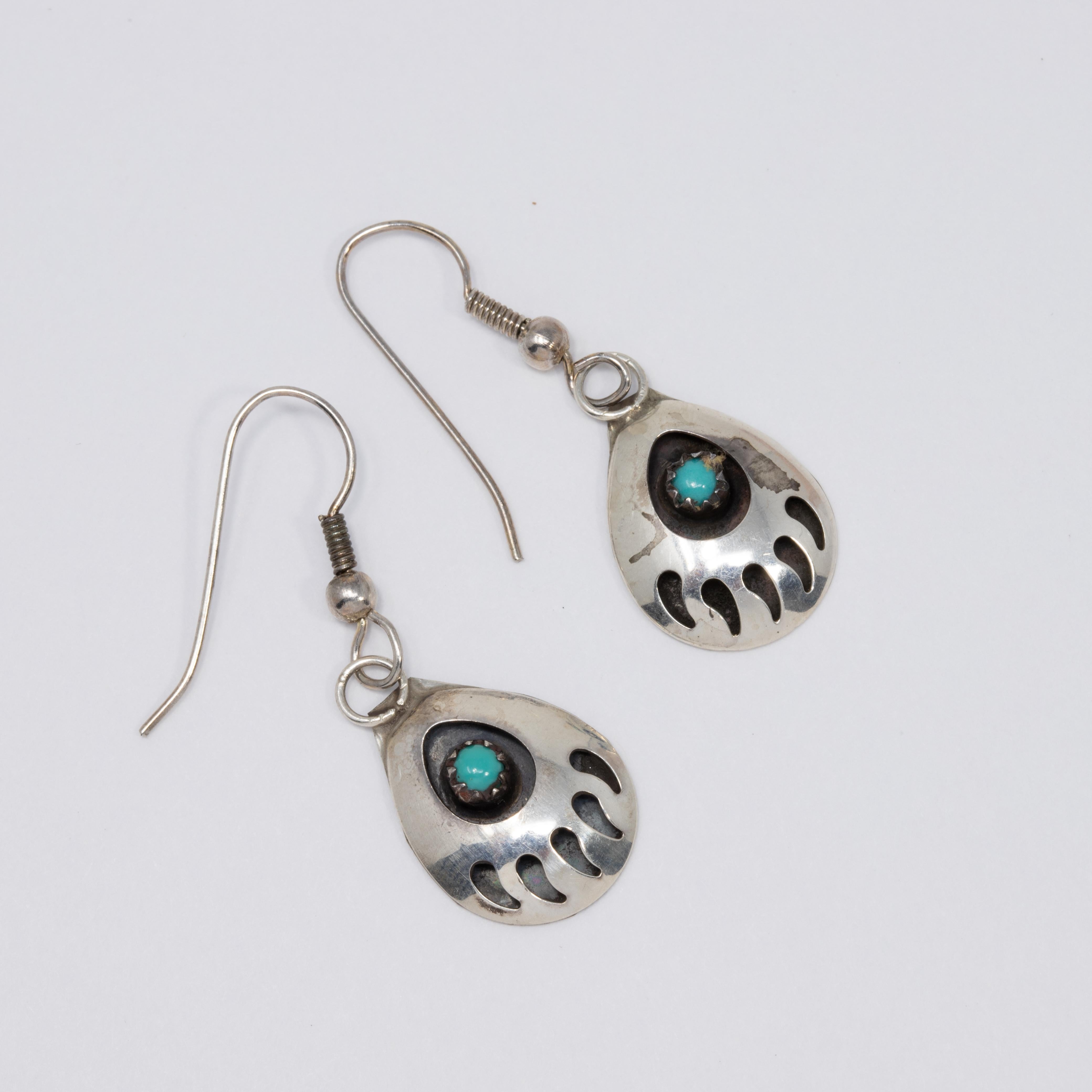 A vintage pair of Native American sterling silver earrings. Each earring features a raised bear claw motif, accented with a turquoise cabochon set in a sawtooth bezel. Excellent Native American craftsmanship!

Hook backs

