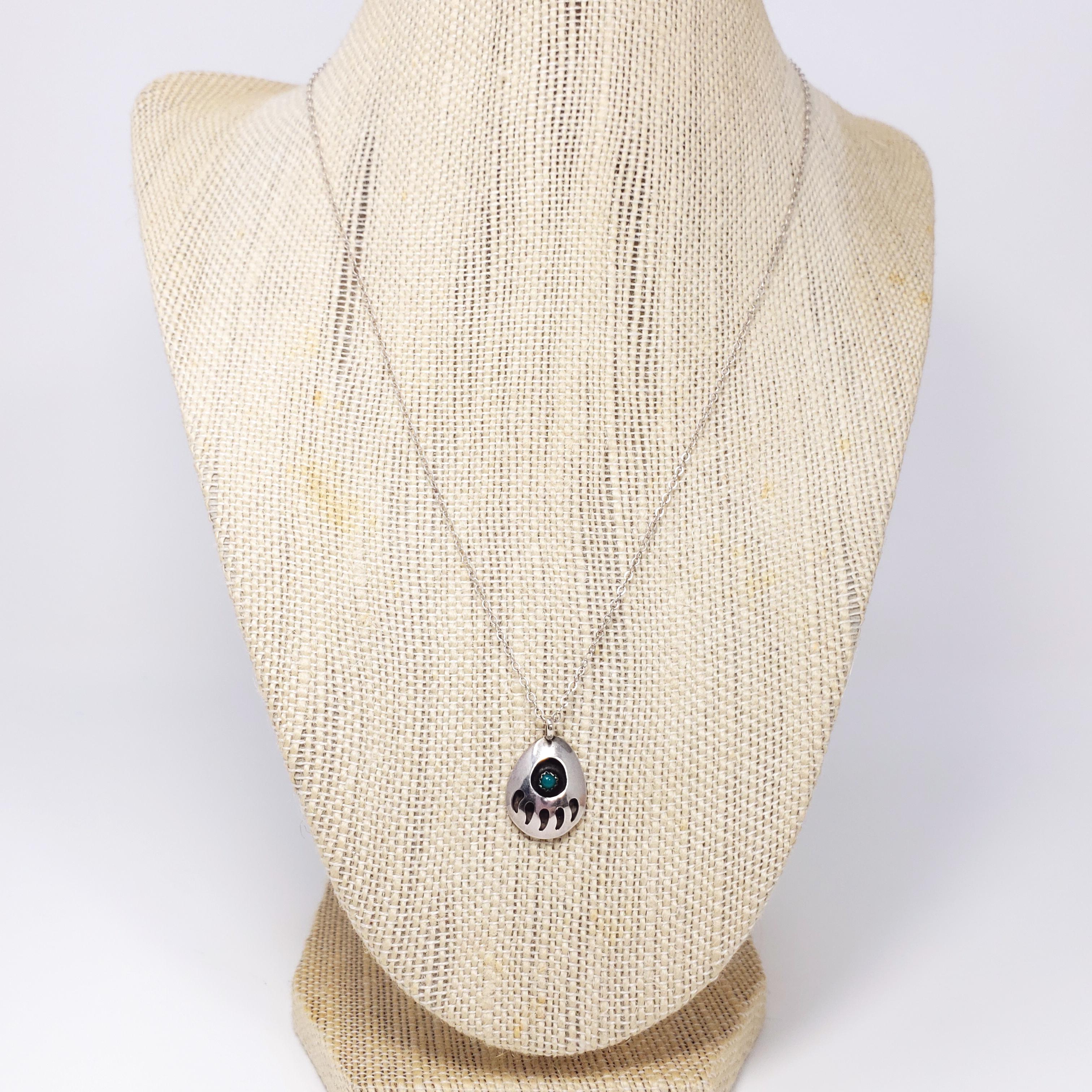 Un collier vintage amérindien en argent sterling. Le pendentif présente un motif de griffe d'ours en relief, accentué par un cabochon de turquoise serti dans une lunette en dents de scie. Excellent artisanat amérindien !

