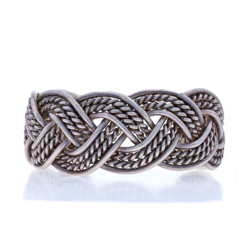 Native American
Artisan: Benny Peralto
Tribal Affiliation: Navajo

Metal Content: Sterling Silver

Bracelet Style: Cuff
Fastening Type: N/A (slides over wrist)
Features: Woven Braid Design

Measurements

Inner circumference (including the opening):