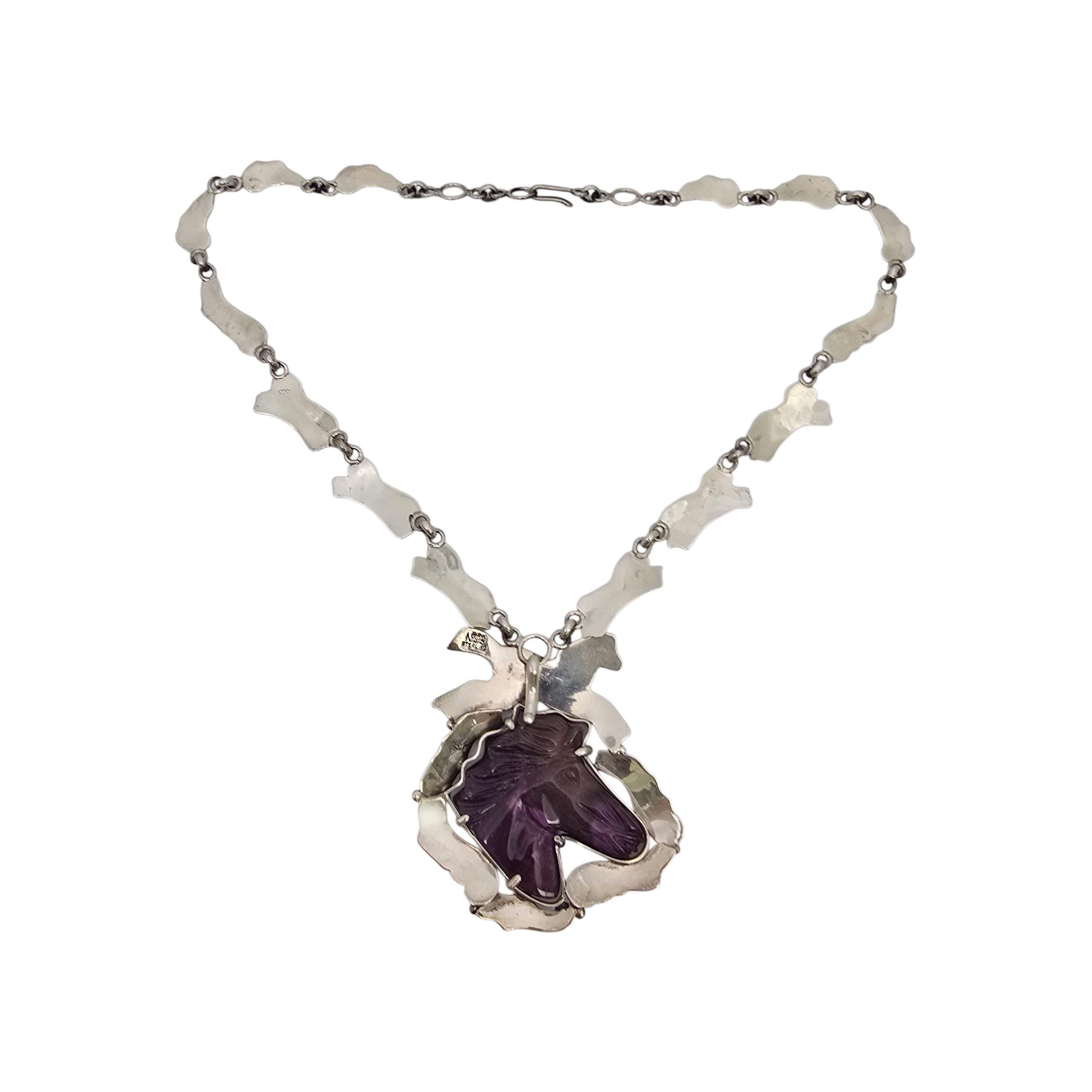 Collana con ciondolo a forma di cavallo in Sugilite d'argento dei nativi americani Dan Nieto

Dan Nieto è un artigiano nativo americano della tribù dei Kewa - Pueblo. Questa bellissima collana presenta un grande ciondolo con una pietra di Sugilite