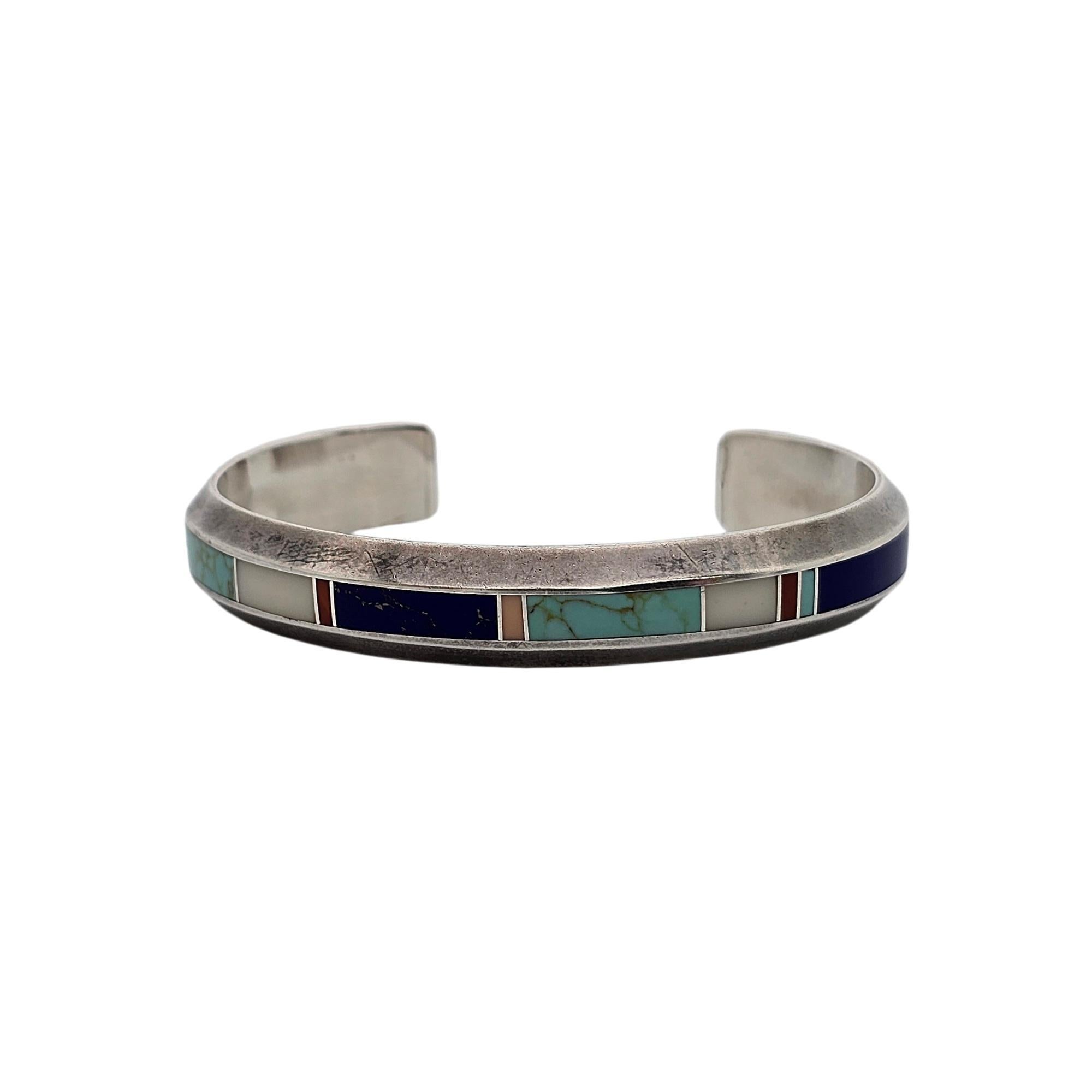 Sterling silver and multi-stone inlay cuff bracelet by Native American Navajo artisan Donald Douglas.

This bracelet features an inlay of multiple stones which appear to me turquoise, lapis lazuli, coral and Mother of Pearl.

Weighs approx 26.5g,