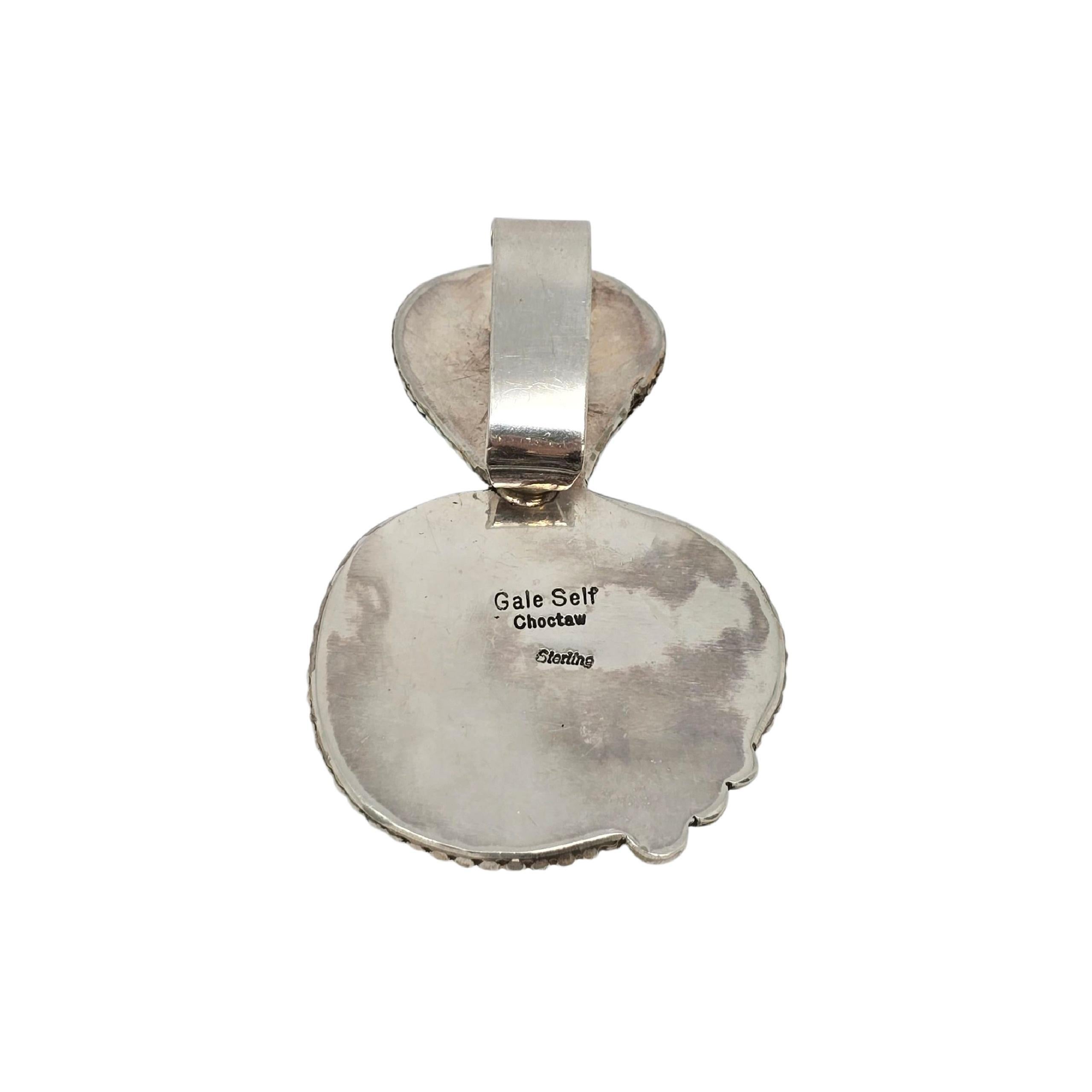 Ciondolo in turchese in argento dei nativi americani Gale Self Choctaw

Questo grande ciondolo presenta 2 grandi pietre di turchese blu incastonate in una cornice di perline d'argento. La balla grande può ospitare catene spesse o corde di