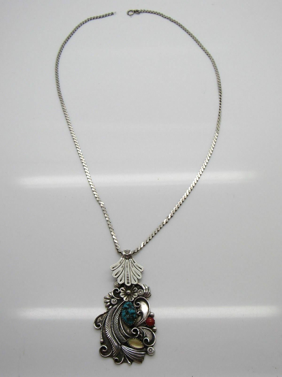 Native American W Jim silver turquoise, coral, and mother of pearl pendant necklace with floral detail.

Marked: unmarked.

Signed: W JIM.

Measures: 23 5/8