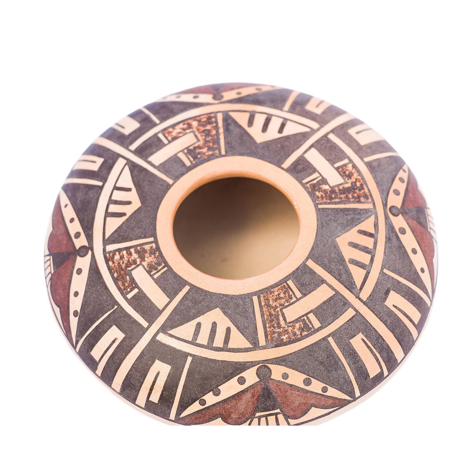 Seed bowl with polychrome geometric and stylised motifs, the base with an inscription of Native American symbols and the word “Hopi” in a dark brown/black color. The center circling designs around the seed bowl have what appears to be stylistic