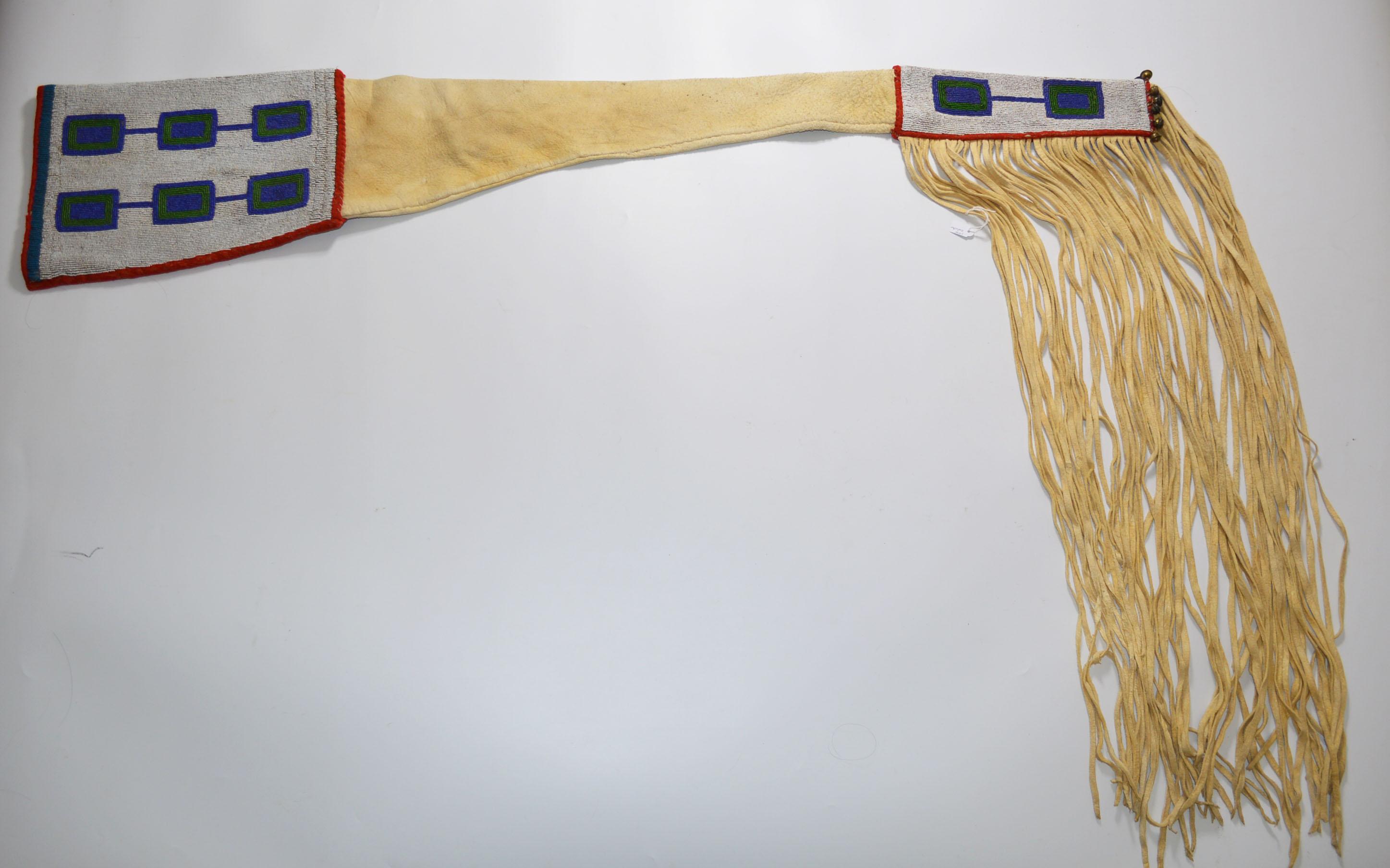A Native American Indian Blackfoot beaded rifle cover
 Buckskin with colored glass beads canvas cloth and bells, 
Finely beaded white background with panels of blue and red linked rectangles
Period: Last quarter of the 19th century
Condition: