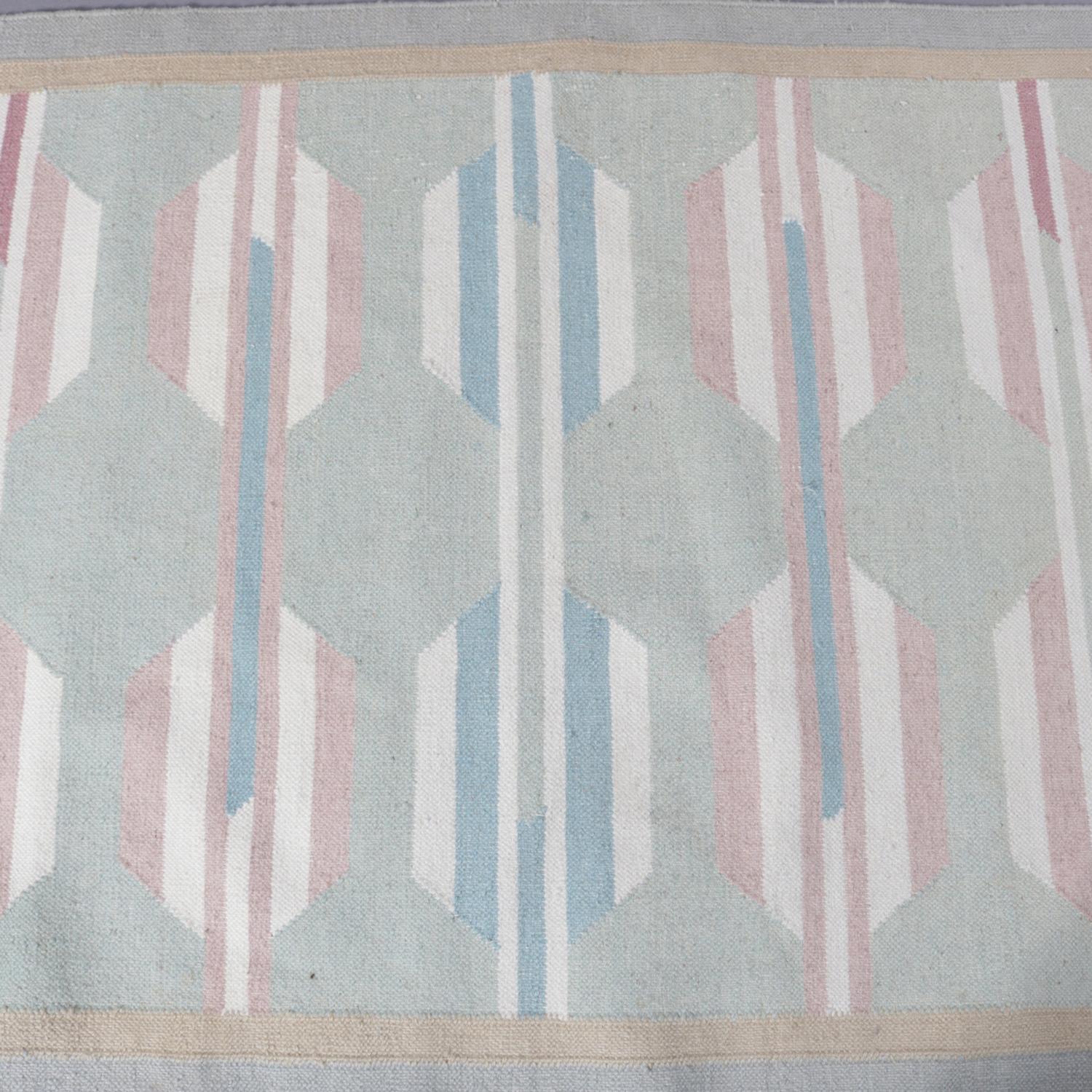 A Native American Indian Navajo style area rug features repeating central geometric design in pastel green, yellow, ivory, pink and blue, 20th century.

Measures: 59