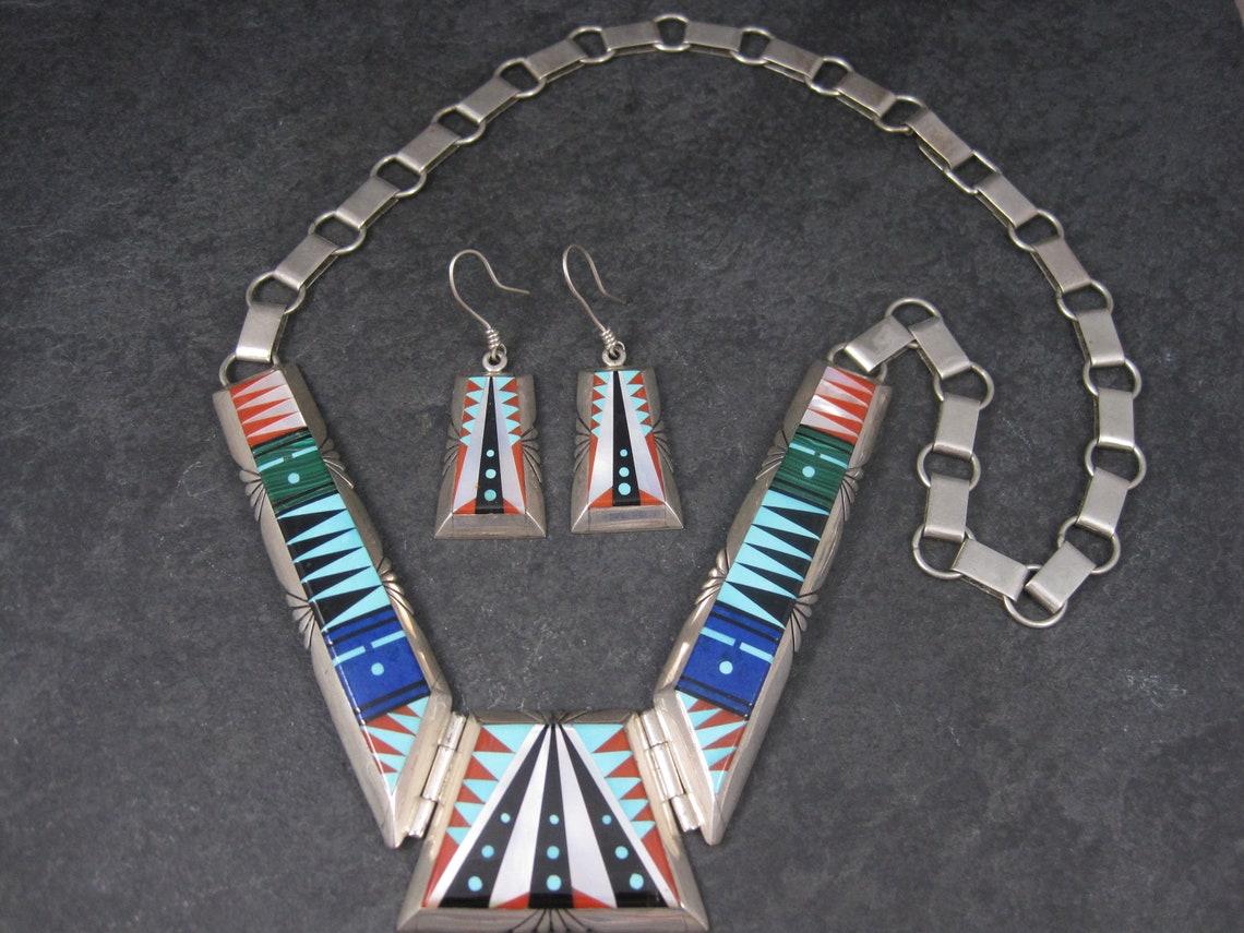 This gorgeous inlaid jewelry set is sterling silver.
It is the creation of the talented Navajo silversmith Chester Benally.

The earrings feature intricate inlay in jet, turquoise, coral and mother of pearl.
Measurements: 3/4 of an inch at their