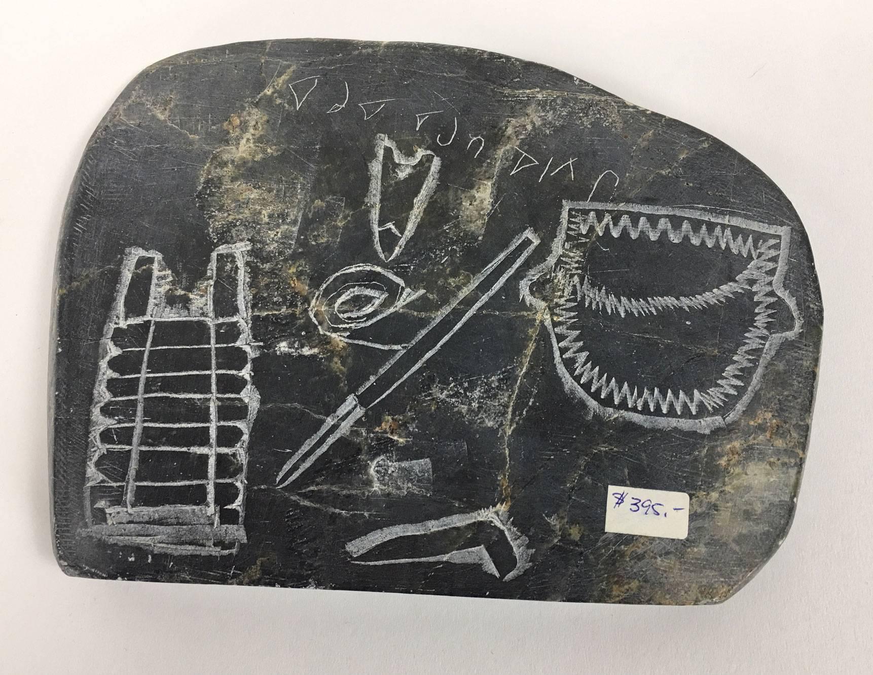 Inuit Eskimo art hunting fishing hieroglyphics stone sculpture carving depicting hand-carved articles of clothing, a parka, pants and glove; sticker marked: Inuit ART CANADA; approx. size: 8.5” x 6.25” x 1”.
 