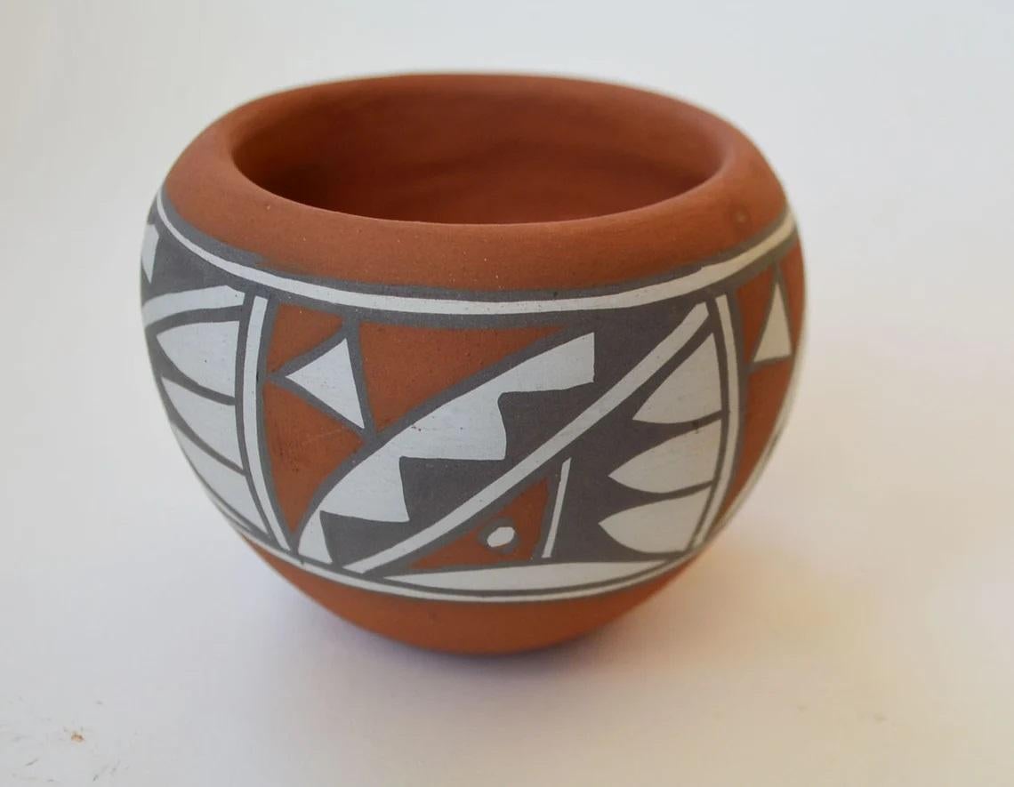 A Native American Jemez pottery pot by Mary Small (b.1940), with hand decorated geometrical pattern frieze on a red clay ground, 
Signed to base, year 86  size 9 cm diameter 6 cm height  3 1/2 x 2/12 inches, 
Mary Small pottery is very collectible