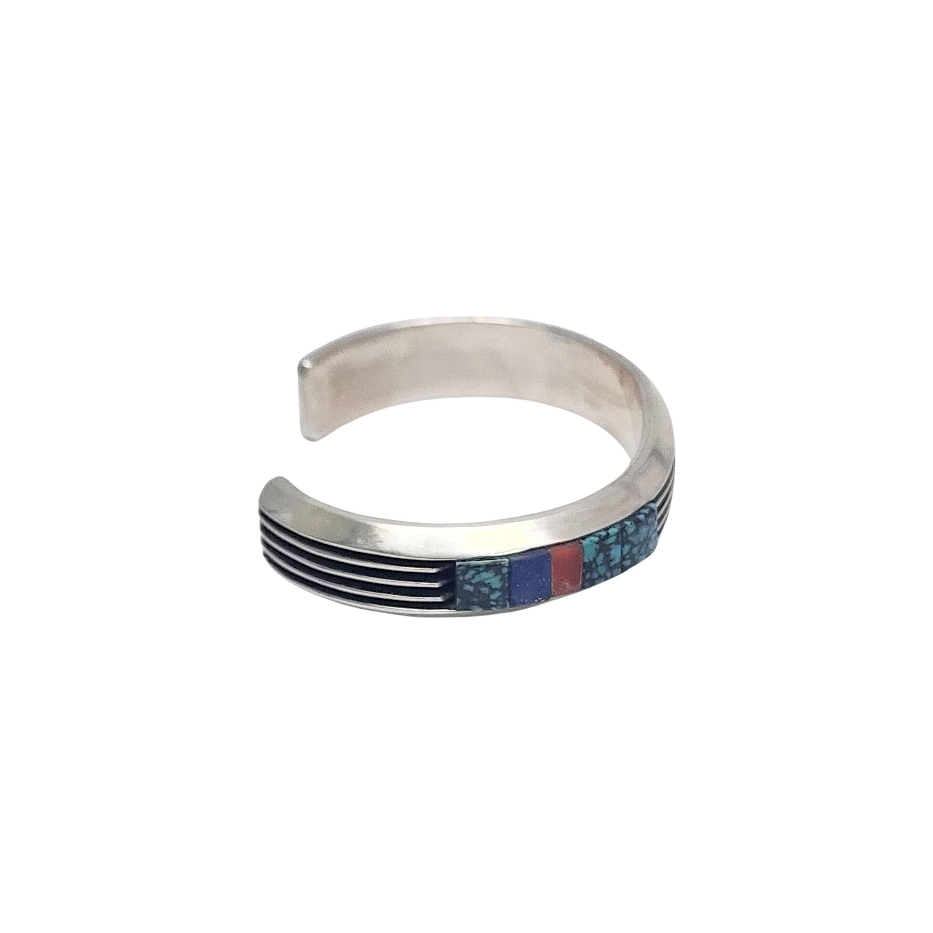 Sterling silver multi-stone cuff bracelet by Native American artisan Larry Begay.

Heavy cuff bracelet with etched line designs and off-set stones on each side that appear to be turquoise, lapis lazuli and carnelian.

Weighs approx 40.5g,