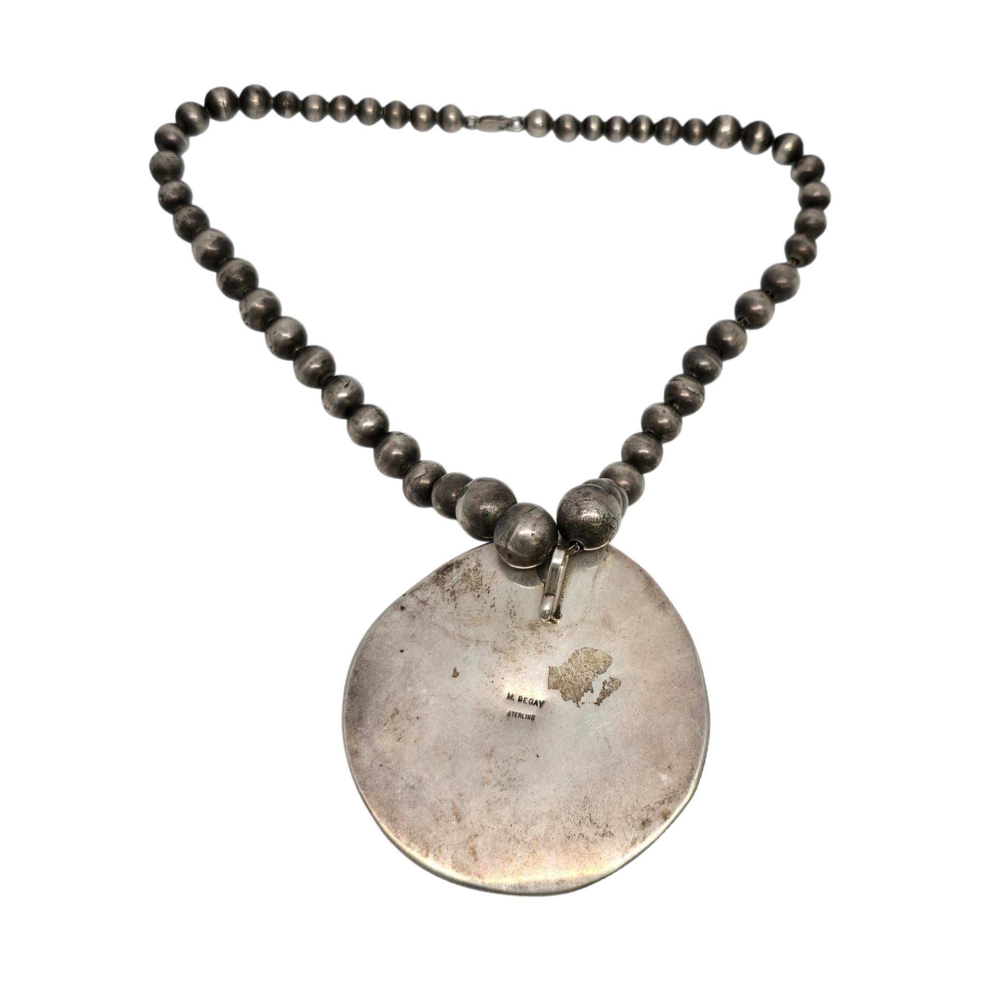 Sterling silver turquoise and spiny oyster bead necklace by Native American artisan, M Begay.

A large and beautiful shell shaped pendant featuring turquoise and spiny oyster in an ornate bezel setting on a chain of graduated round bench