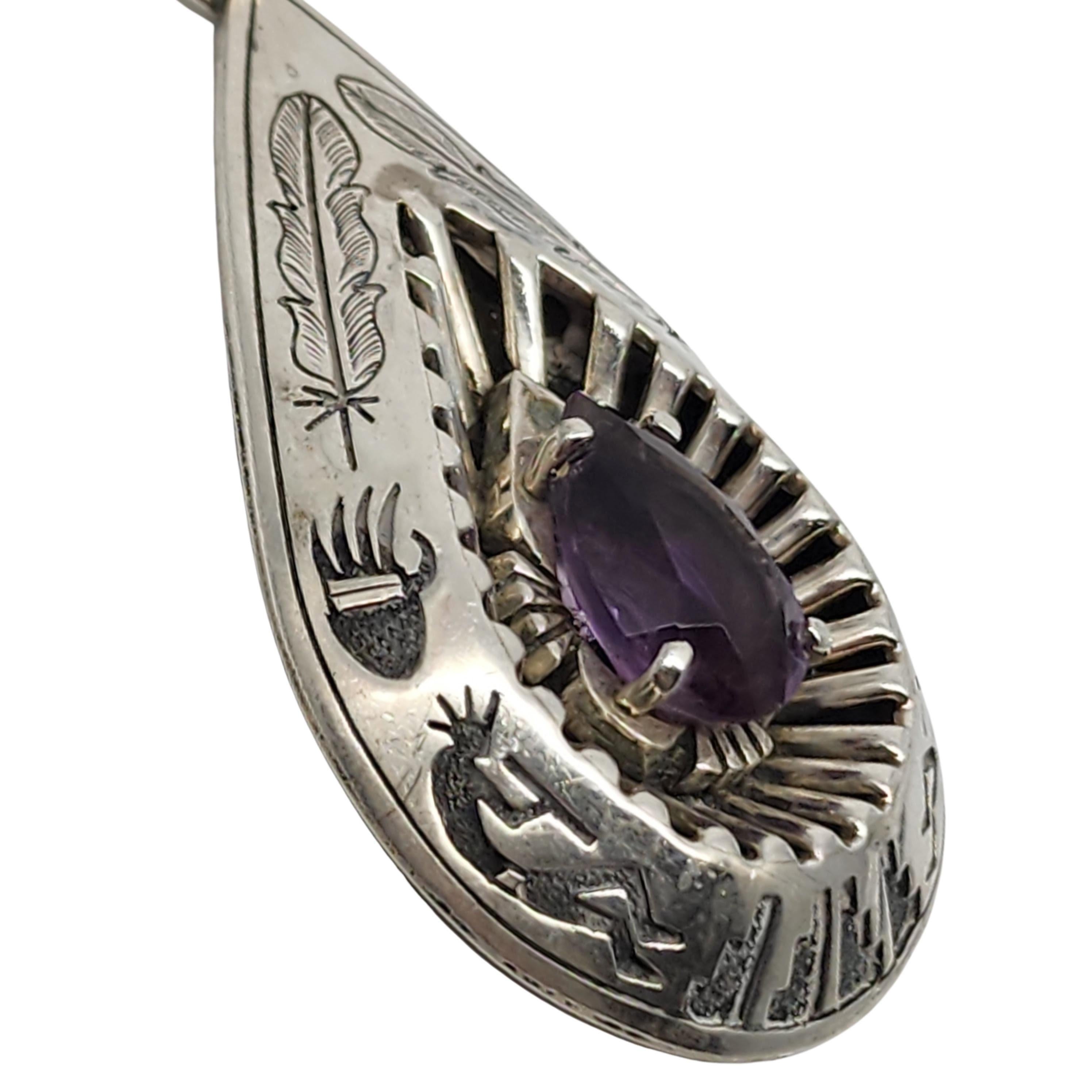Ciondolo a goccia in argento sterling con ametista dell'artigiano nativo americano Navajo, Mark Yazzie.

Grande ciondolo a goccia con simboli dei nativi americani: piume, artigli d'orso e montagne. L'ametista viola a goccia sfaccettata è incastonata