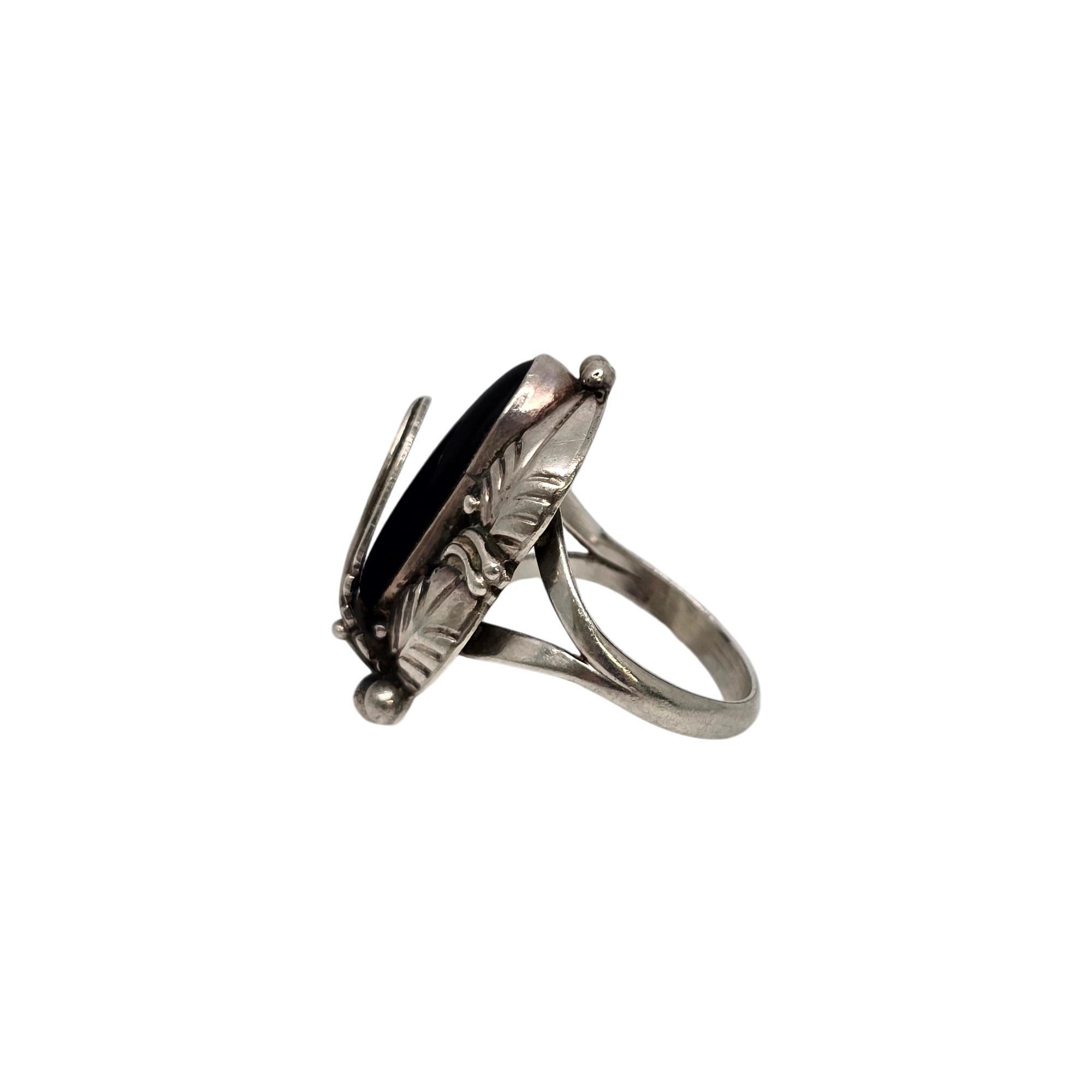 Sterling silver onyx feather ring by Native American Navajo artisans Grace and Gilo Nakai.

Size 7 1/4

This piece features a long and narrow oval onyx stone bezel set with bead and feather accents.

Weighs approx 6.4g, 4.1dwt

Measures approx 1