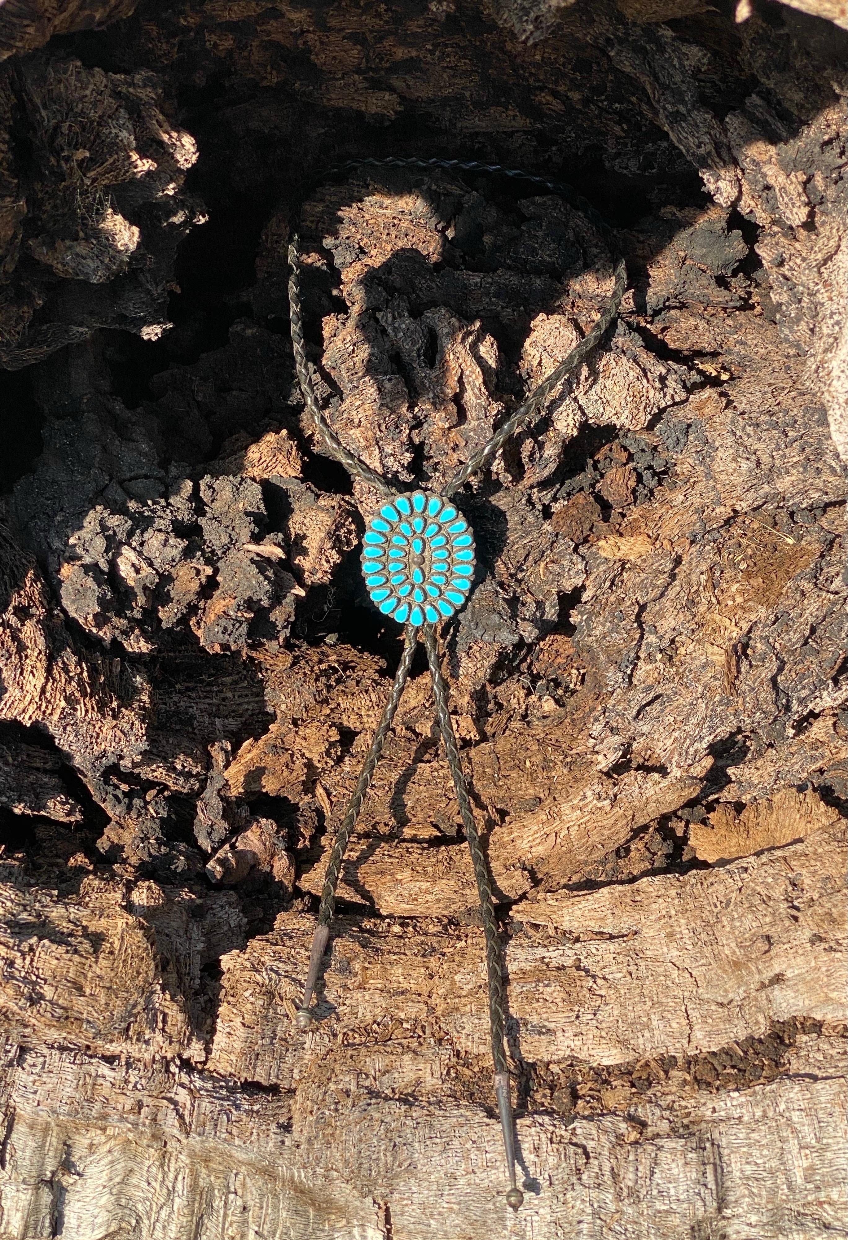Cravate bolo fabriquée par les Navajo au Nouveau-Mexique dans les années 1950. Fabriqué à la main à partir d'argent .900 et serti de turquoise, la corde est en cuir tissé à la main et les pointes sont en argent.