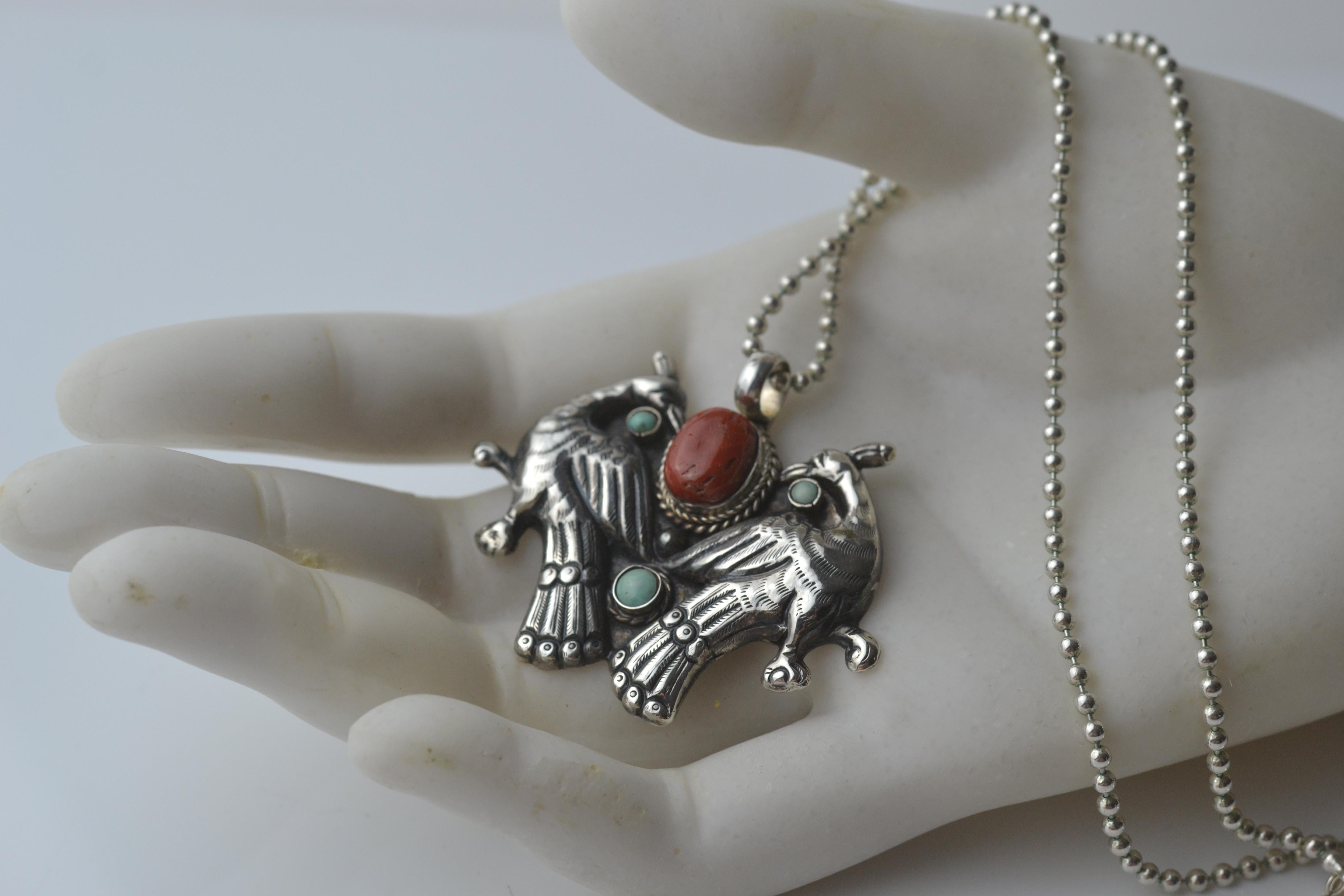 This is a beautiful and striking piece, talisman design, marked on the reverse 925 for sterling silver, with a lovely high central cabochon of old coral as the centrepiece and two opposing birds with turquoise bezel set  stones.  As you can see, it
