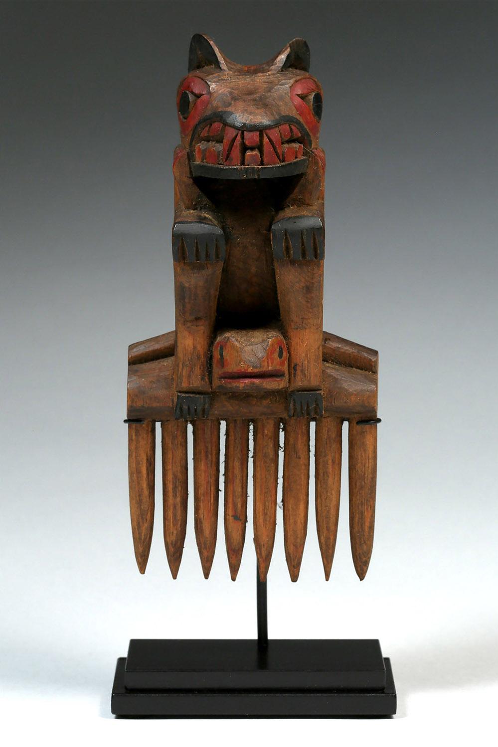 Early 20th Century Native American Northwest Coast Bear Comb, Probably Tlingit

The comb depicts a bear seated on a frog. The bared teeth are stylistically carved, with classic eye treatment and its features accentuated in traditional red and black