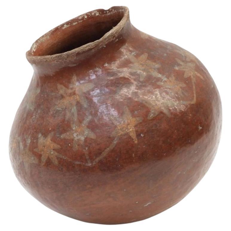 Native American large squat red earthenware pottery vase decorated with flower motif around shoulder of vessel.