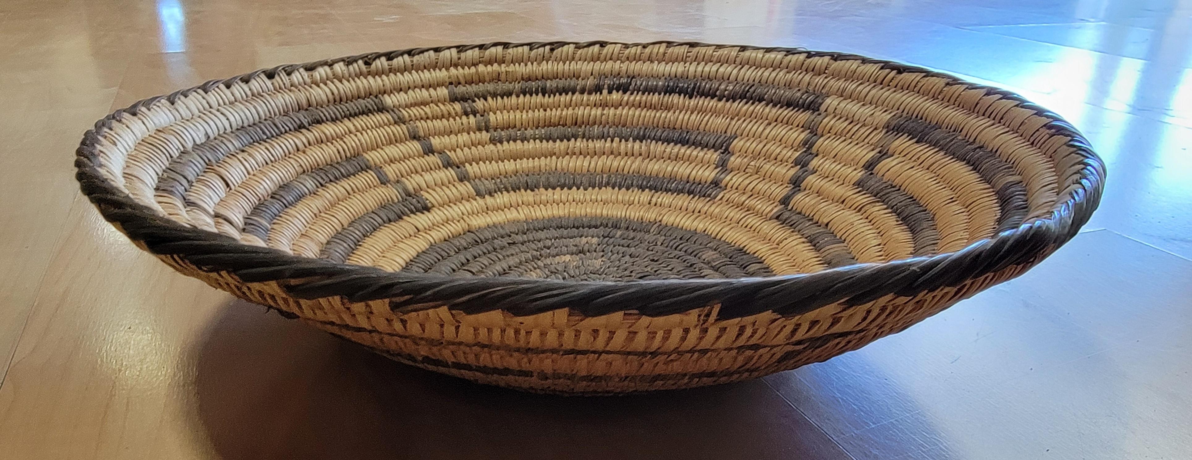 A hand woven Native American basket with a geometric pattern. Crafted by the Papago Tribe of Arizona which changed their name to the Tohono Oʼodham Nation in 1986. Very good original condition, no repairs. 

10.88 Inch Diameter.
2.63 Inch High.