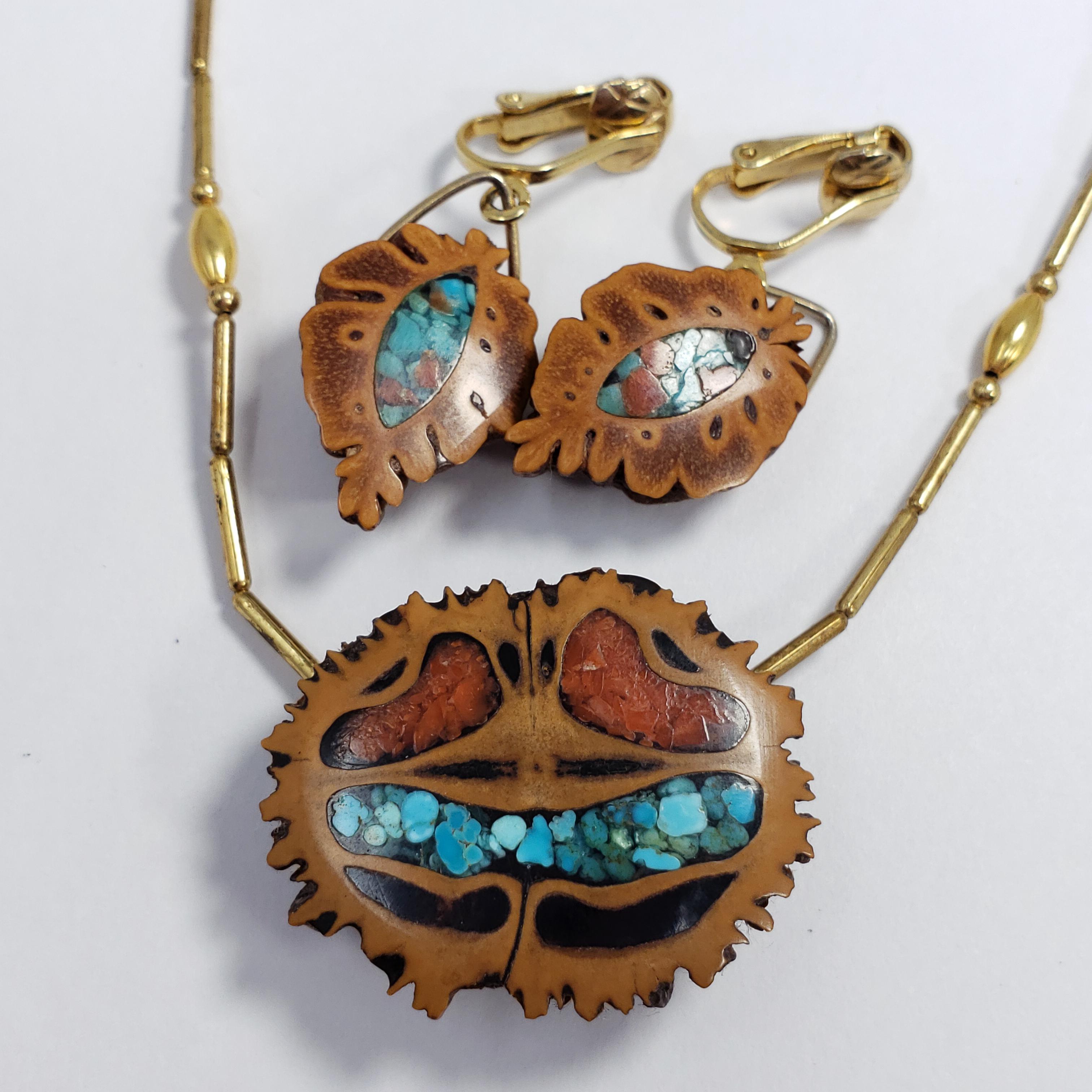 Eine Halskette mit Anhänger und ein Paar Ohrringe in einem stilvollen Design. Die Halskette besteht aus einem Anhänger aus Walnussholz, der mit Korallen und türkisfarbenen Akzenten verziert ist, und einer goldfarbenen Stabkette. Die Clip-Ohrringe