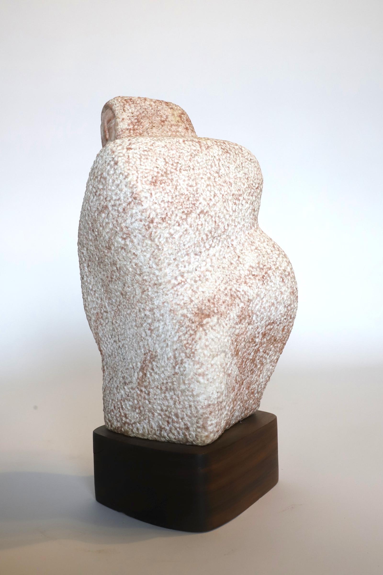 Simplistic Native American pink granite sculpture on wood base. Piece is signed. Photographed with Eames chair for scale. Wood base photographed darker. See photos.