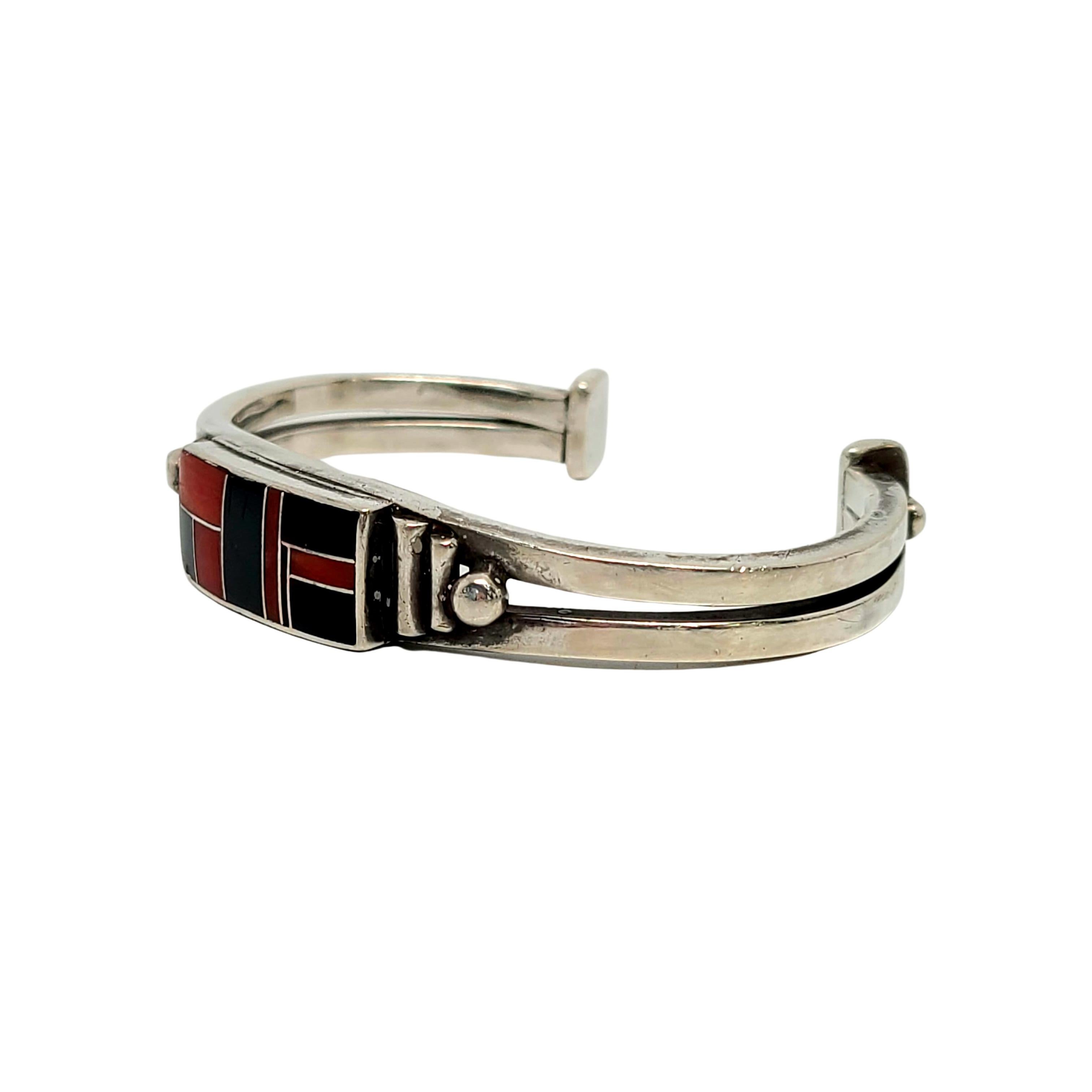 Sterling silver and multi-stone inlay cuff bracelet by Native American Navajo artisans, Ray Tracey and Knifewing Seguara.

Beautiful channel inlay mosaic of what appears to be onyx and coral stones. A collaboration of well known contemporary Navajo