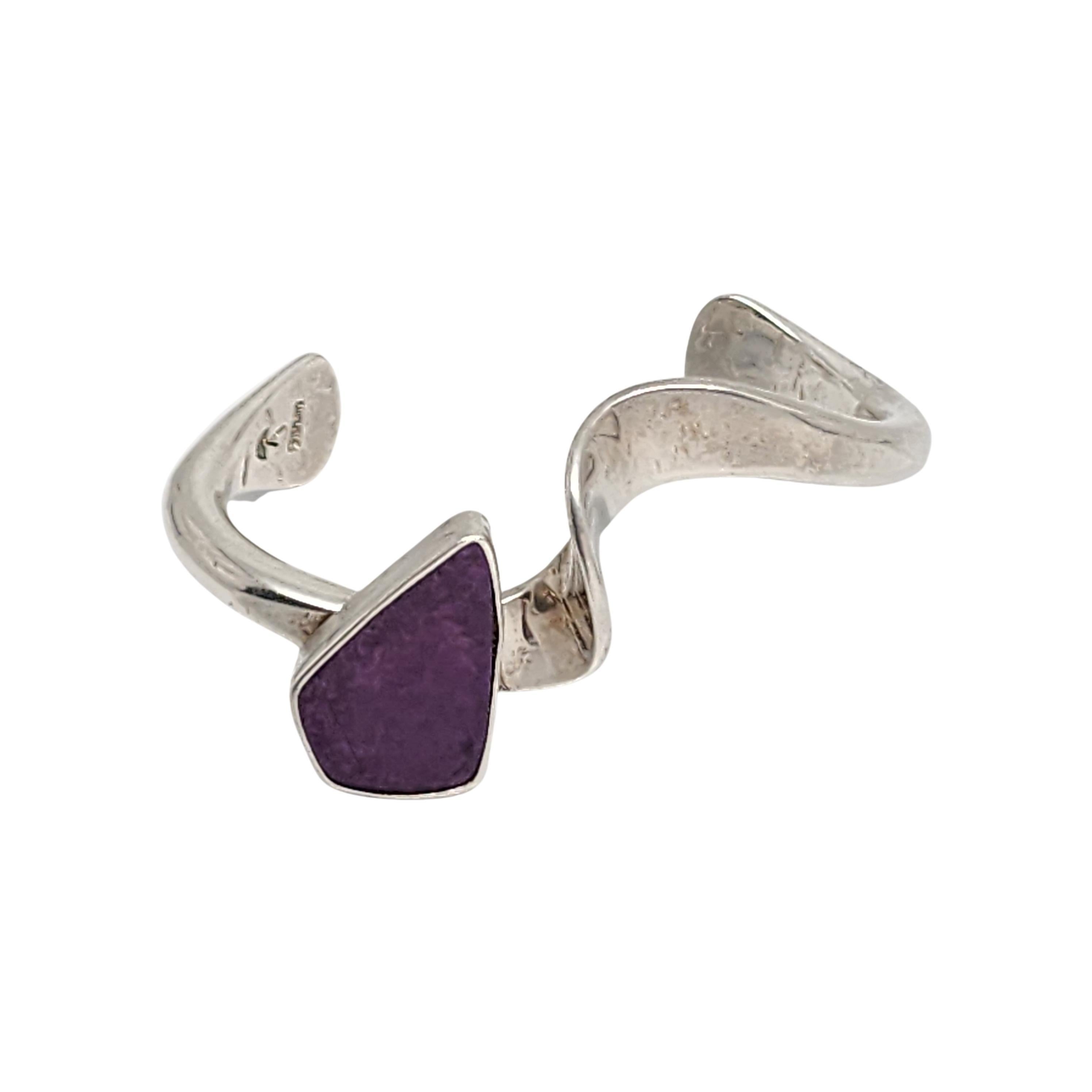 Sterling silver sugilite cuff bracelet by Native American artisan Richard Aguilar.

Unique twist design featuring a large purple sugilite stone by Santo Domingo Pueblo artisan Richard Aguilar. 

Measures approx 5 1/4