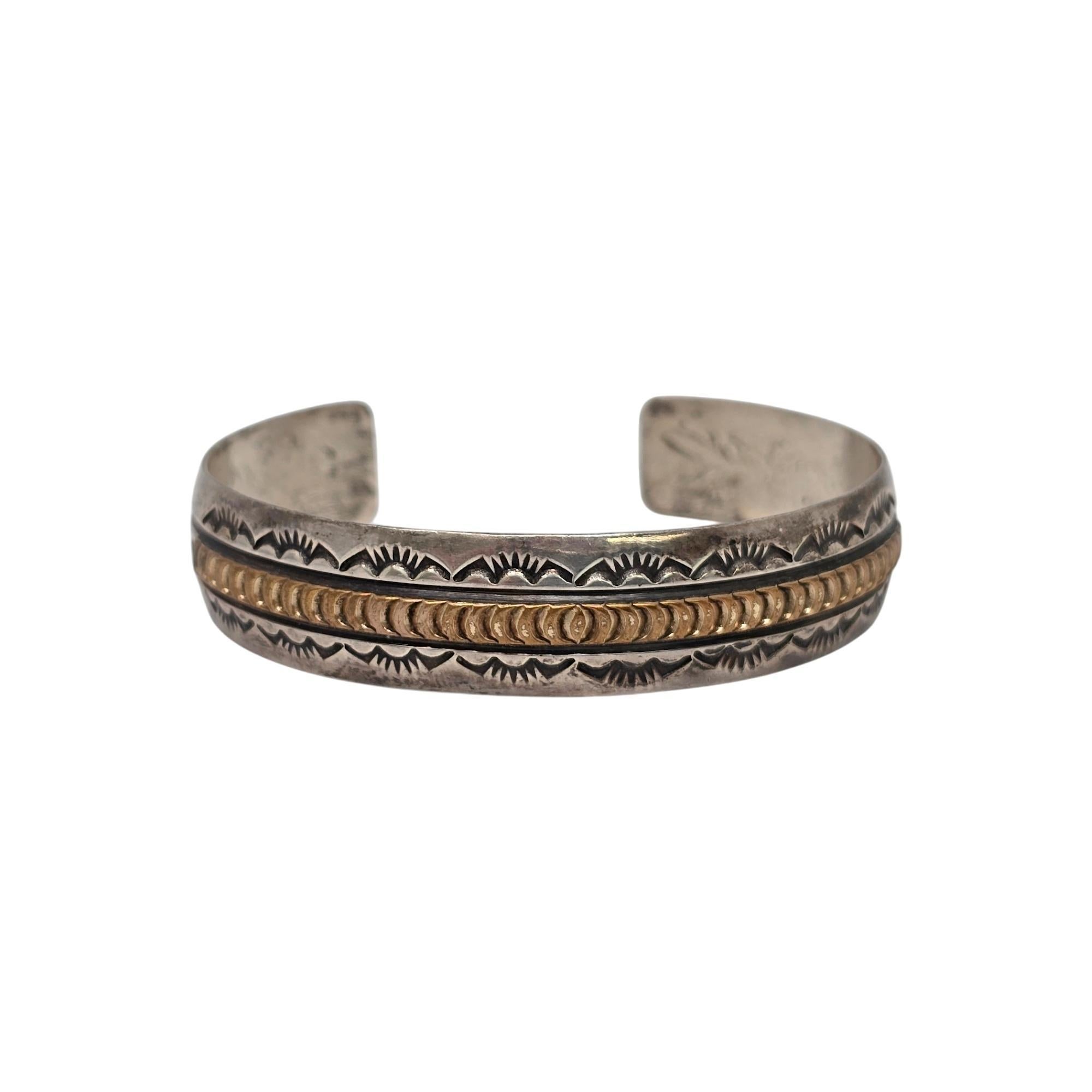 Bracelet de manchette en argent sterling et or signé Native American.

Signée de la lettre R, cette pièce est un bel exemple de travail sur l'or. Le bracelet manchette en argent sterling est orné d'une barre dorée au centre, d'accents estampés et de