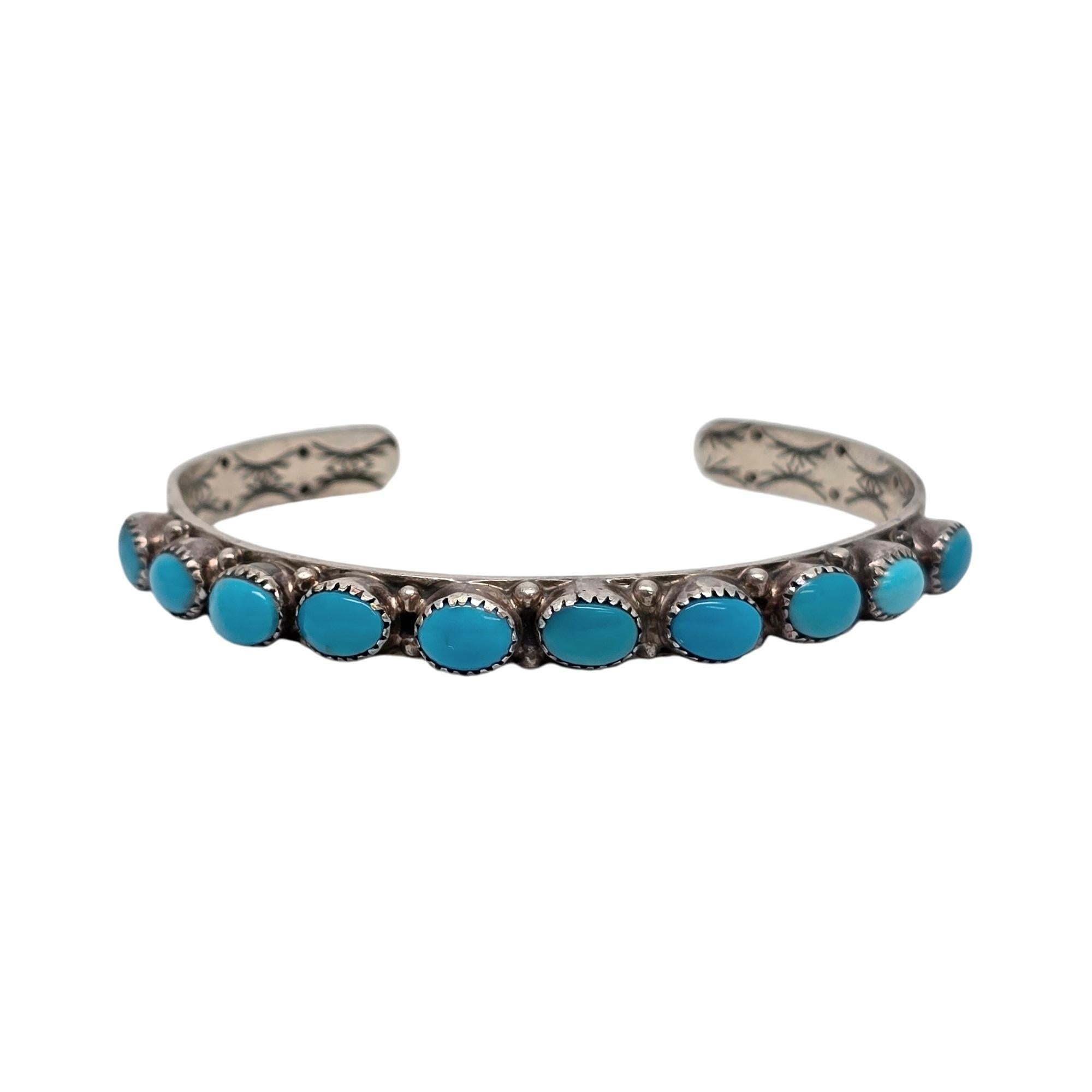 Sterling silver and turquoise cuff bracelet by Native American artisan signed WR.

This bracelet features a line of horizontally set oval turquoise stones in a saw tooth bezel with small bead accents between each stone. Stamped design on the inside