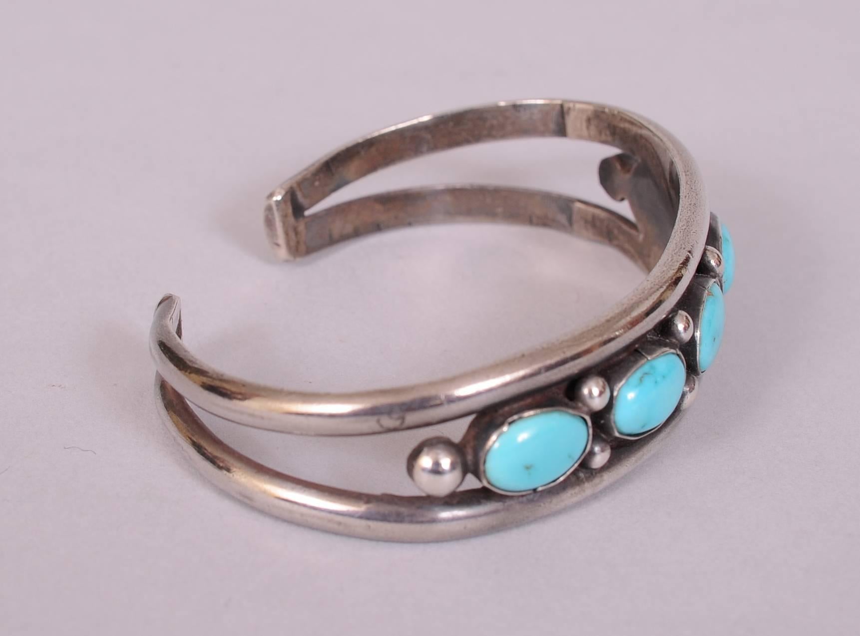 Five nice turquoise stones are enhanced by sterling silver balls and held in place by sterling bands at the top and bottom. These bands join together on the back of the bracelet. It has a lovely patina, but would be easy to polish if you desire a