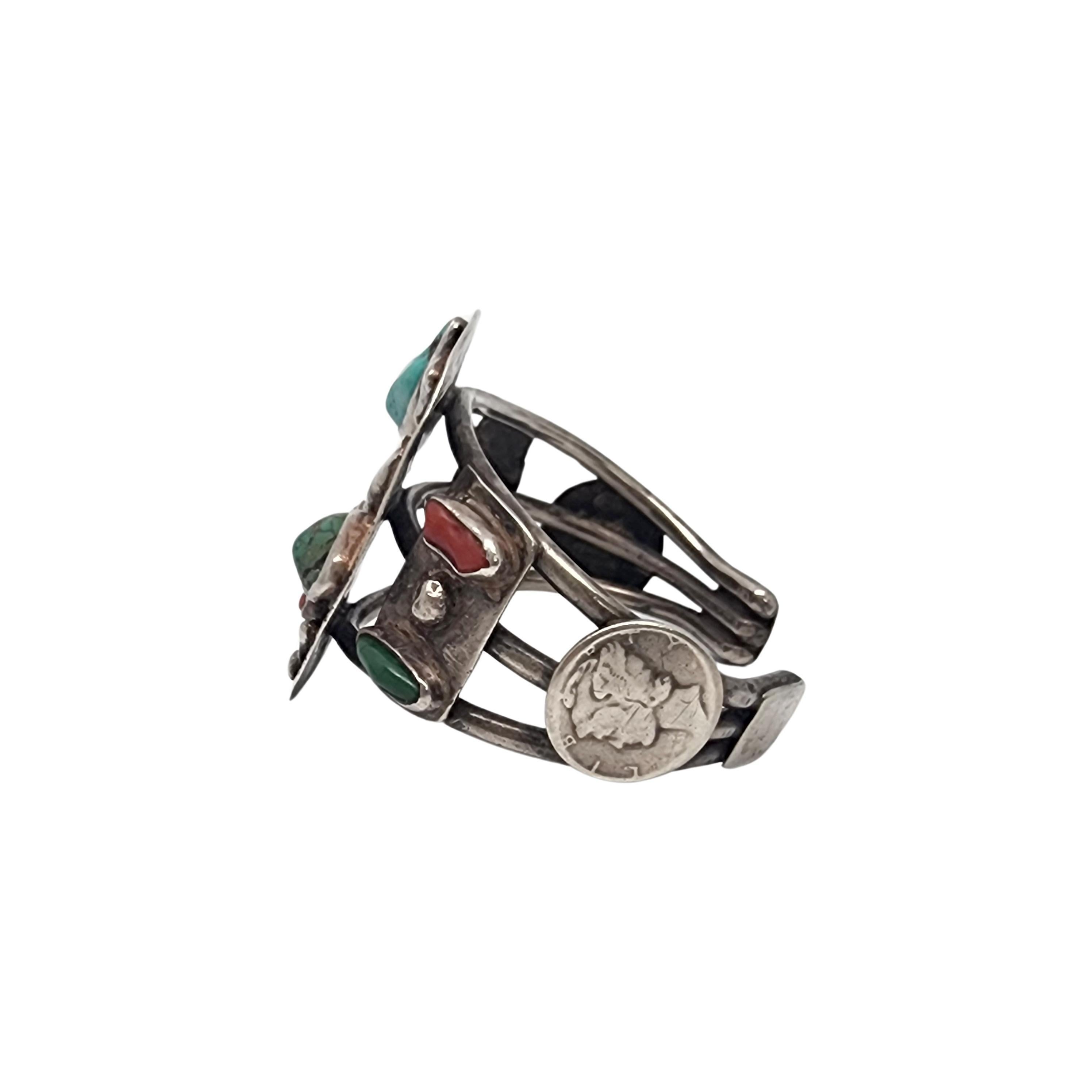 Silver and turquoise and Mercury dime cuff bracelet by Native American artisan.

This large and substantial piece features bezel set blue and green turquoise and red coral in a modernist design. A mercury dime is on each side.

Weighs approx 72.9g,