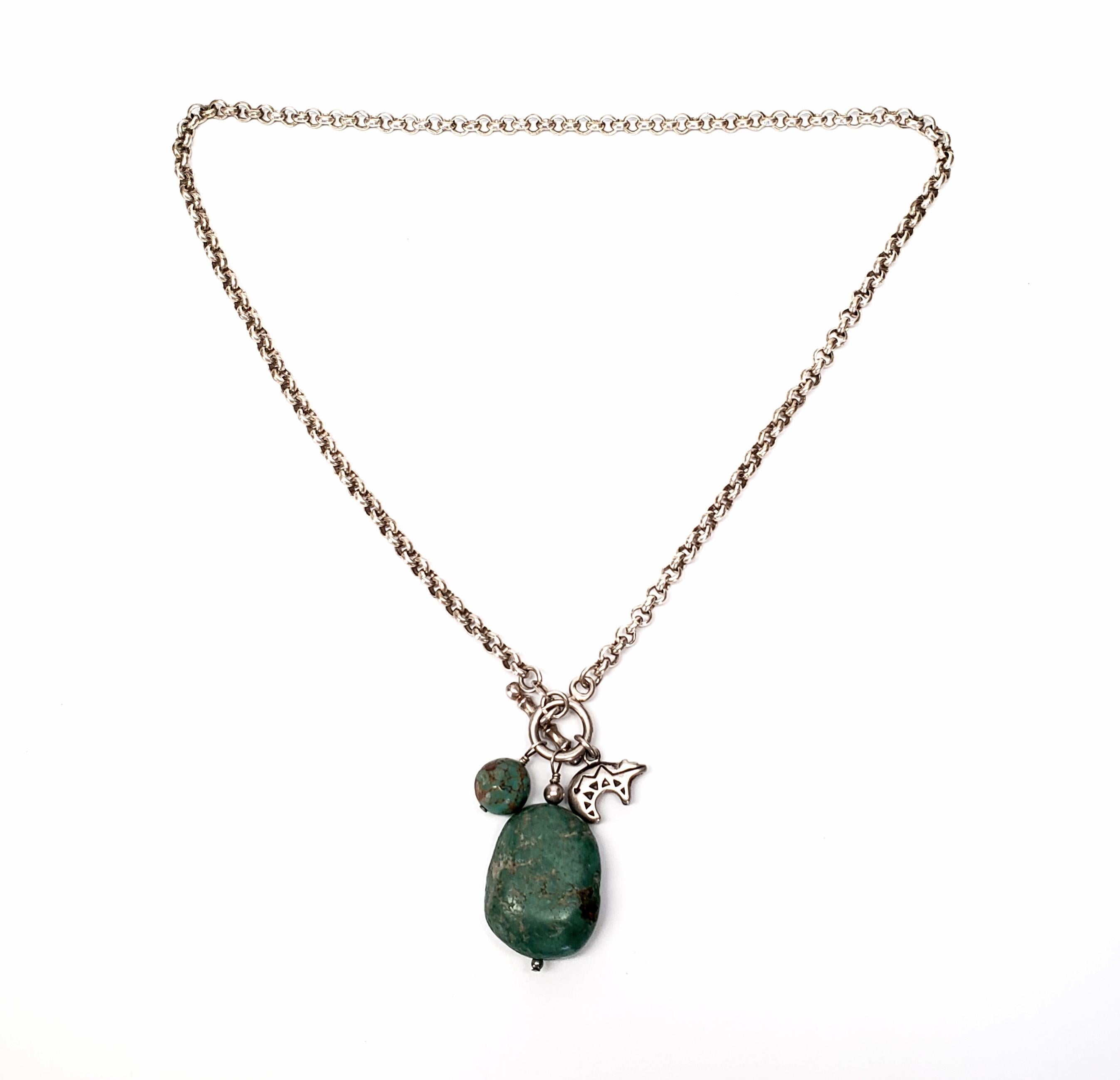 Native American sterling silver and turquoise nugget necklace with small bear charm.

Circle link chain necklace with green turquoise nugget and bead, and a small etched Native American bear charm. The bear symbolizes a fierce warrior and great
