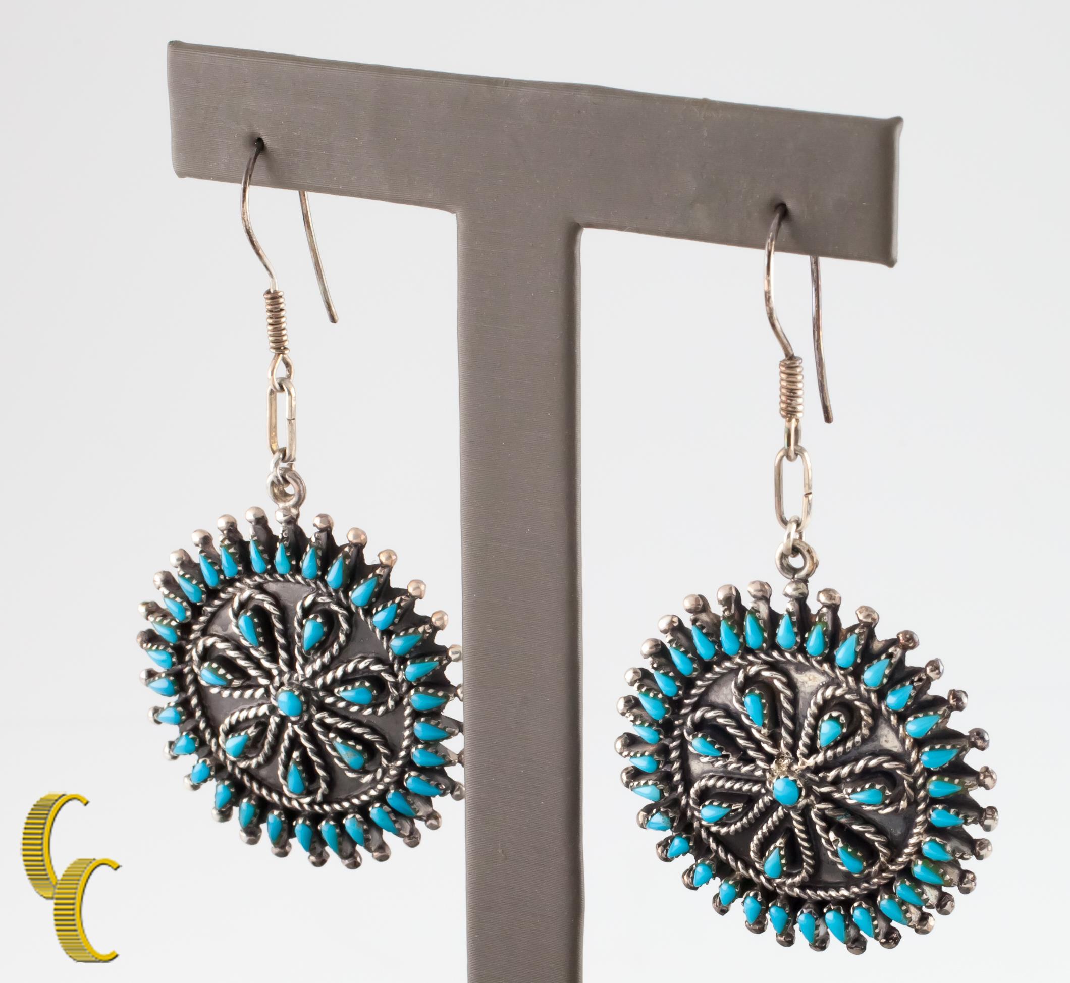 Native American sterling silver wheel dangle earrings.
Features turquoise set on silver.
French loop hook fasteners.
Diameter: 35 mm.
Metal: 0.925 sterling silver.
Weight: 15.2 grams.