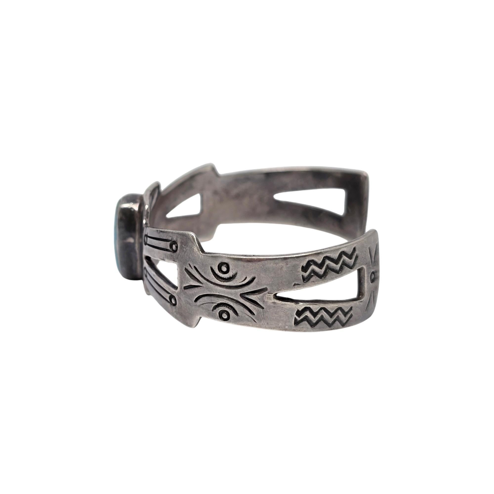 Sterling silver and turquoise cut-out cuff bracelet, signed by a Native American artisan.

This bracelet features an oval turquoise stone bezel set with a cut-out design and stamped designs on both sides.

Measures approx 5 3/4