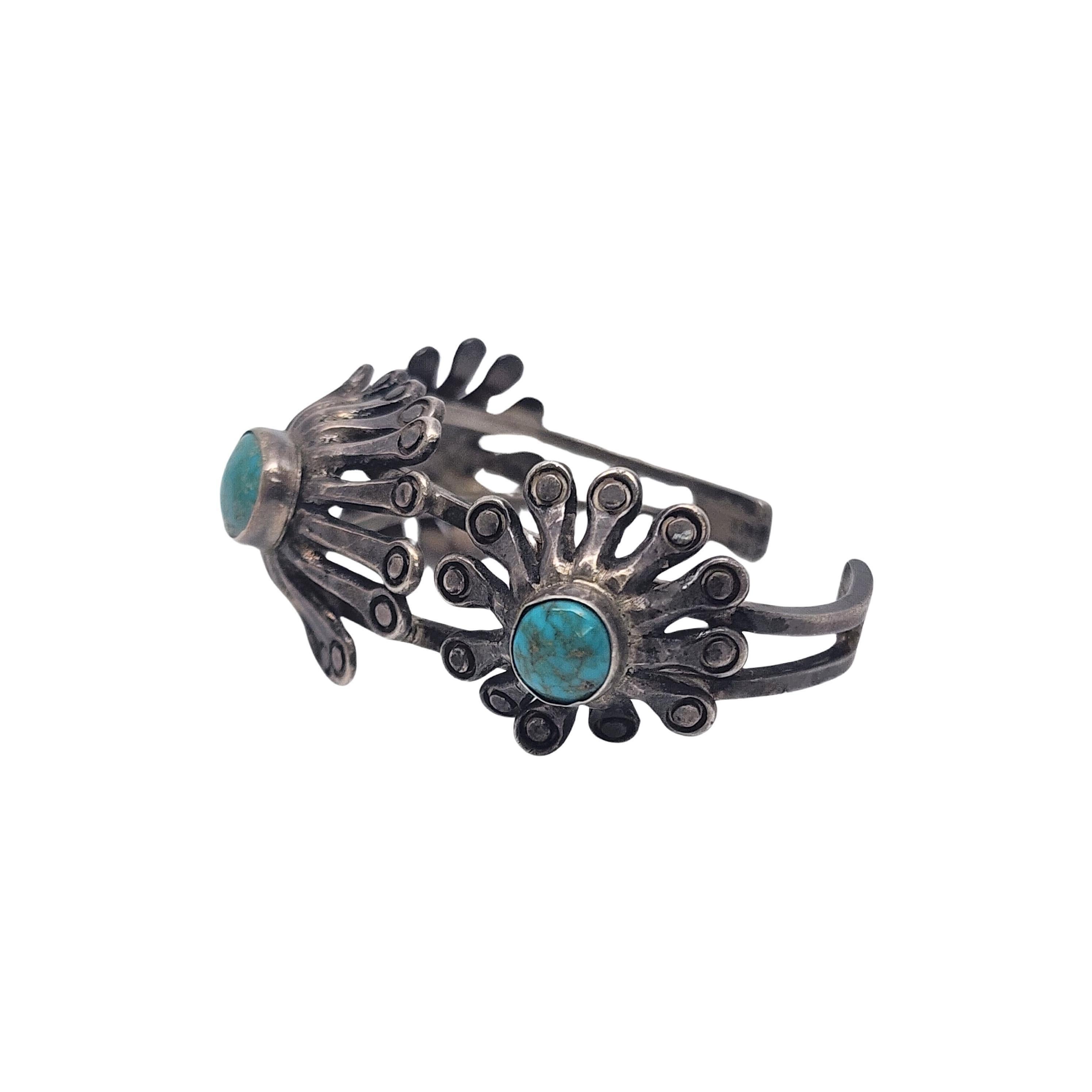 Sterling silver and turquoise modern flower design cuff bracelet by Native American artisan, signed by what appears to be ABKI (see photo).

This bracelet features bezel set turquoise stones surrounded by a modern flower design.

Weighs approx