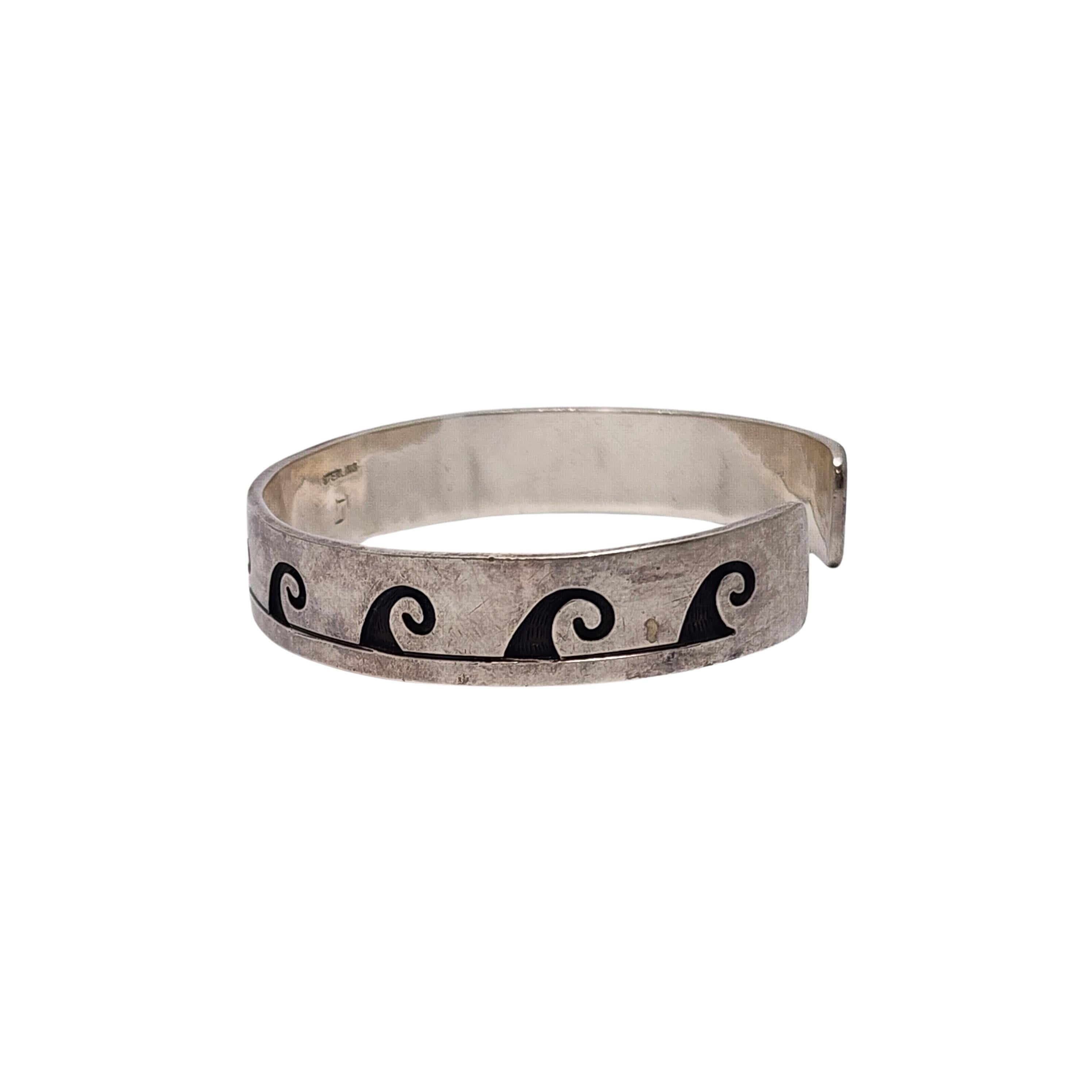 Bracelet manchette en argent sterling avec des vagues superposées par un artisan amérindien.

Cette pièce présente un motif de vagues dans la technique de l'overlay.

Pèse environ 24.3g, 15.6dwt

Mesure environ 6 3/4