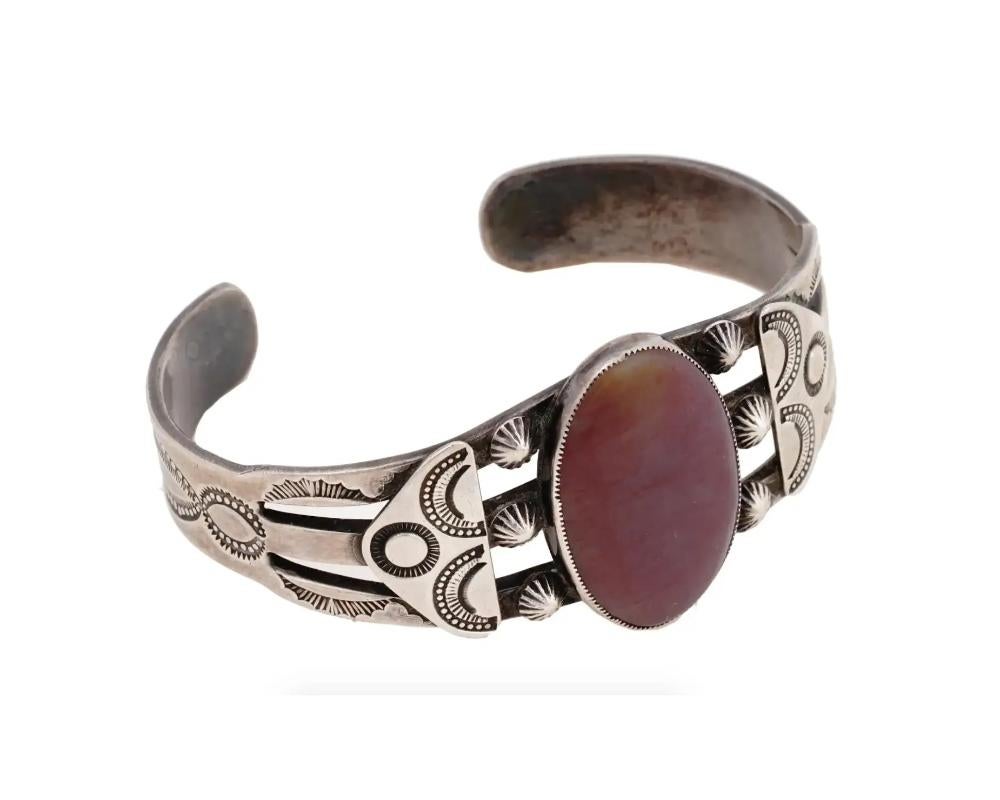 A Native American Navajo Sterling Silver bangle cuff. The bangle cuff is encrusted with oval cut Spiny Oyster, and decorated with relief and engraved traditional ornaments. Circa: 1960s. Vintage and Modern Native American Ethnic Jewelry, Silverware,