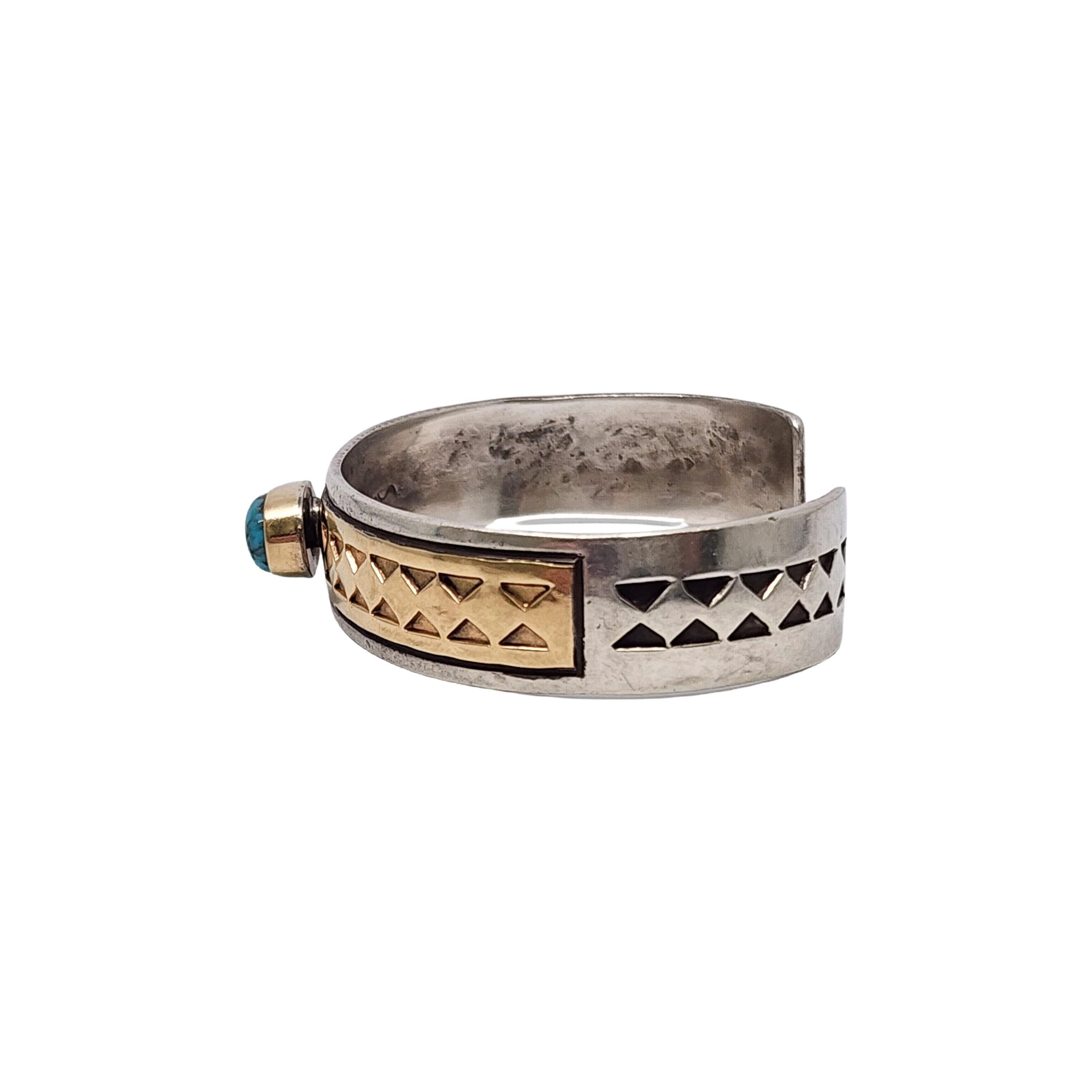 Sterling silver 14K turquoise cuff bracelet by Native American artisan Tillie Jon.

An oval turquoise stone is bezel set on a 14K yellow gold plate over a sterling silver cuff bracelet featuring beautiful stampwork on the gold and silver.

Weighs
