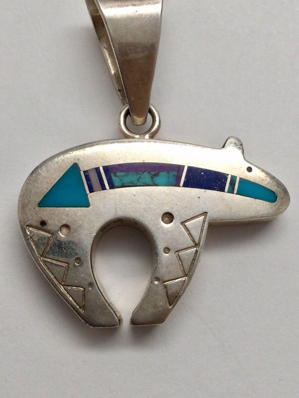 Native American Tracey Knifewing sterling silver inlay spirit bear pendant.

Marked: hallmark, Sterling

Measures: 1