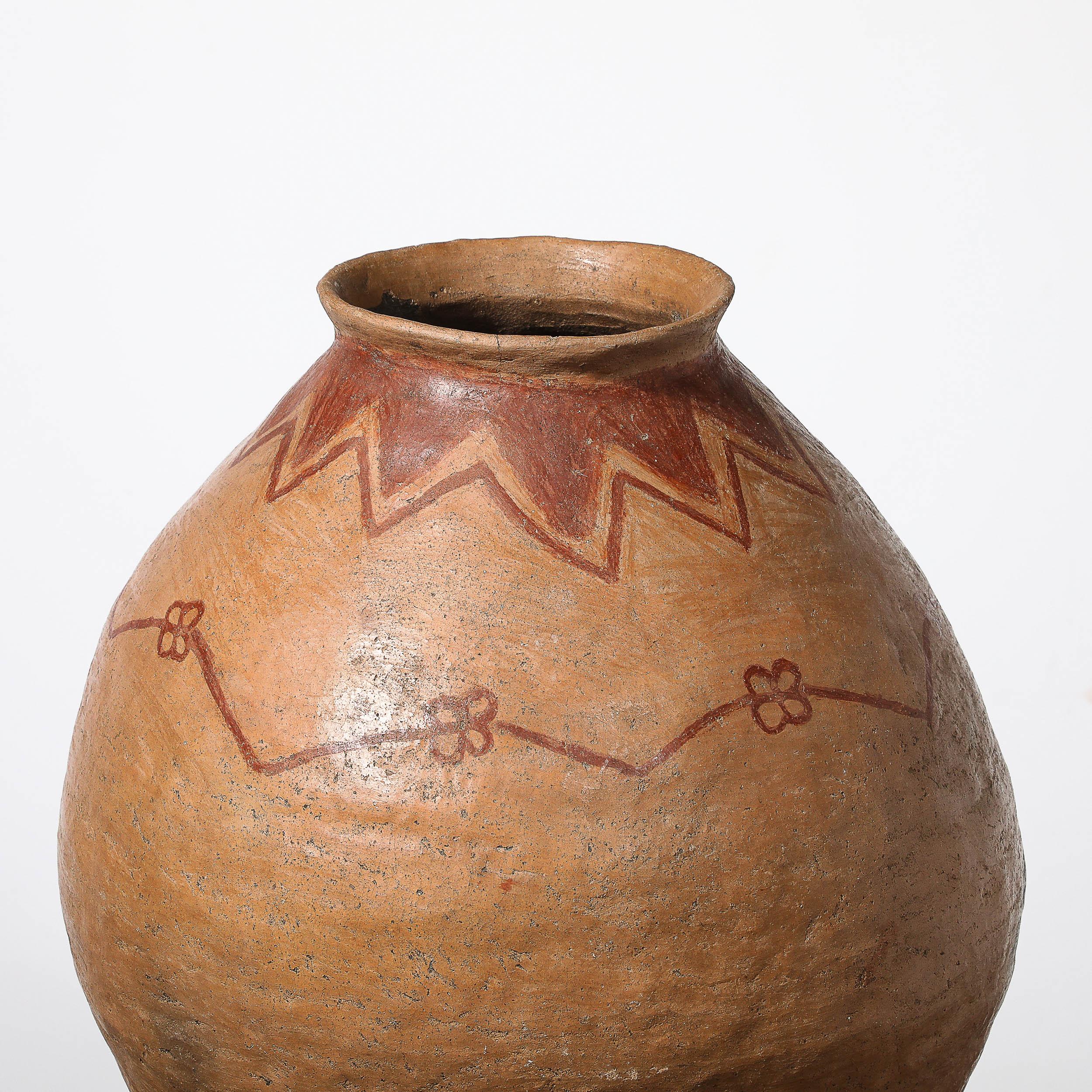 Questo straordinario vaso tribale dei nativi americani del XX secolo mette in mostra la maestria e l'eredità culturale dell'artigianato dei nativi americani. Realizzato in terracotta, presenta intricati dettagli dipinti all'ossido di ferro rosso che